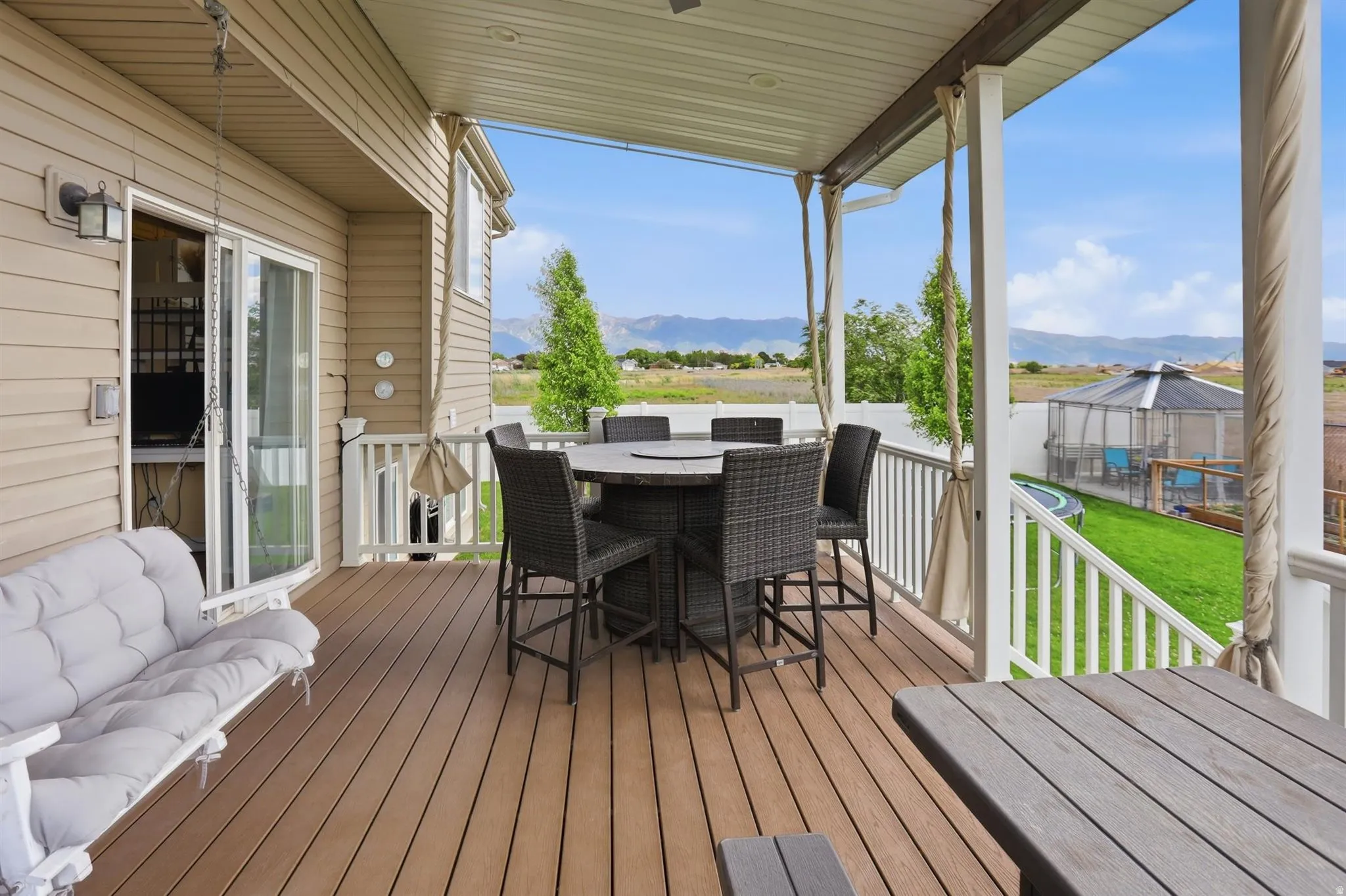Expansive covered deck featuring wood-finish flooring, white railing, and a sliding glass door for interior access