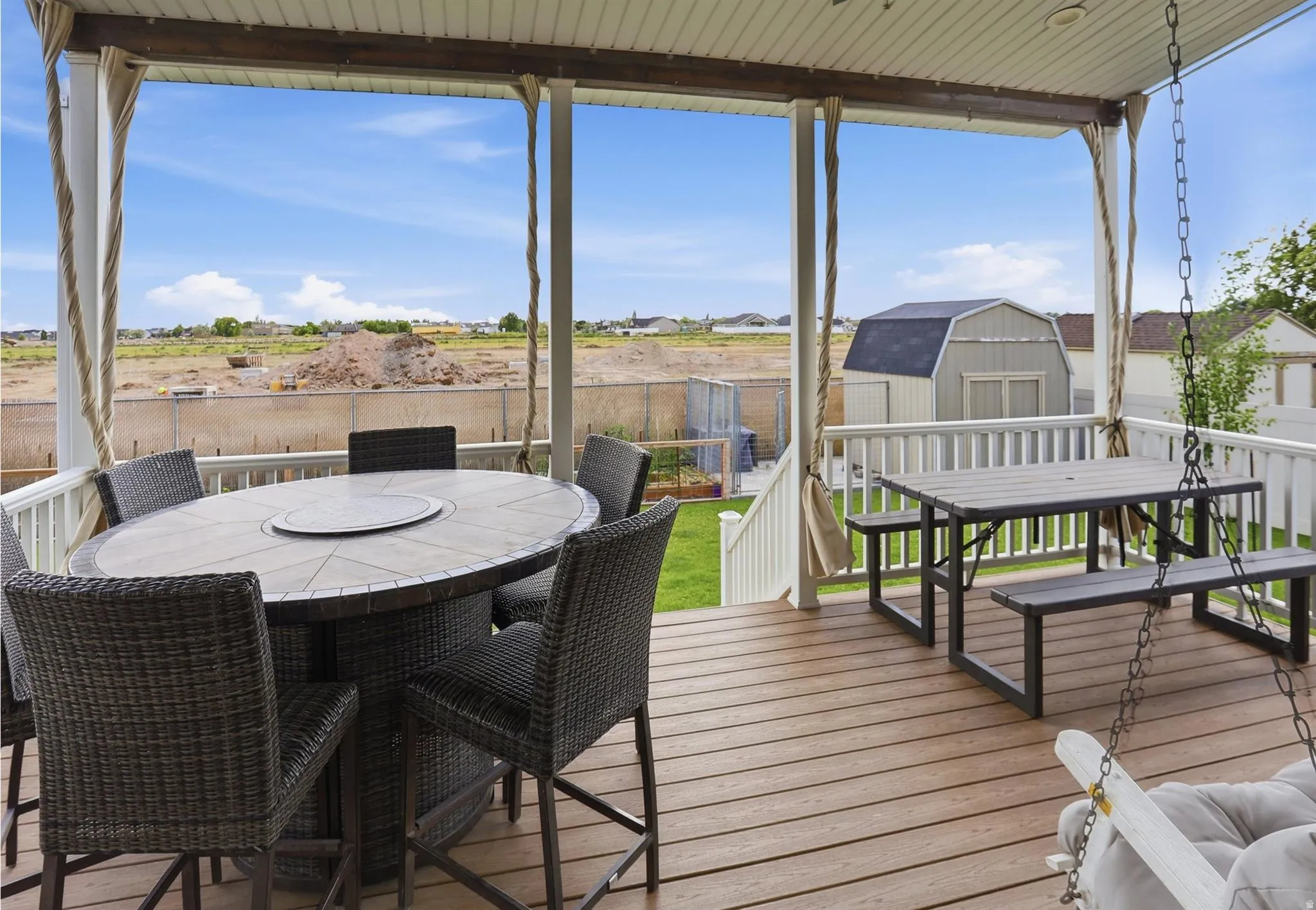 Covered outdoor deck featuring composite decking, white railing, and a storage shed visible in the yard