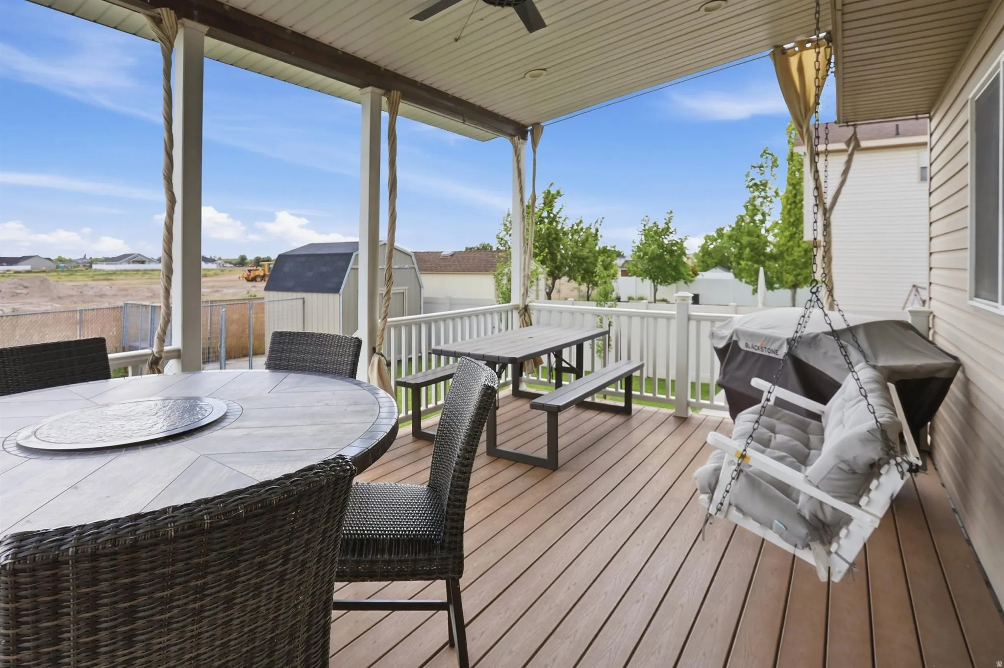 Spacious covered deck featuring composite decking, white railing, and exterior siding