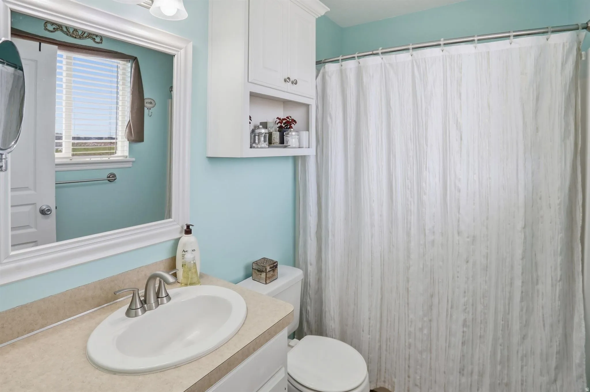Primary Bathroom featuring a vanity with a drop-in sink, brushed nickel faucet, and a light-toned countertop