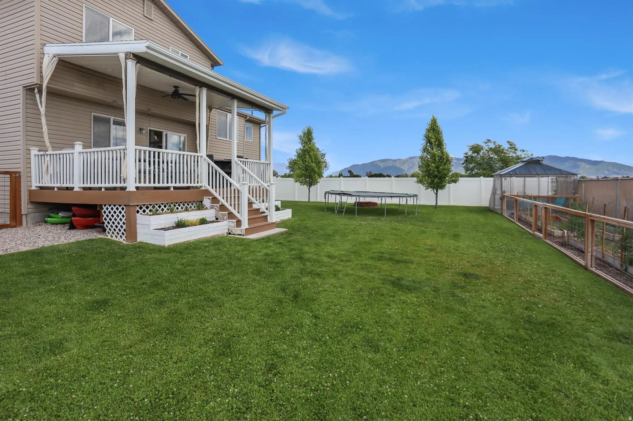 Expansive green lawn with a covered wood-finish deck and white railing