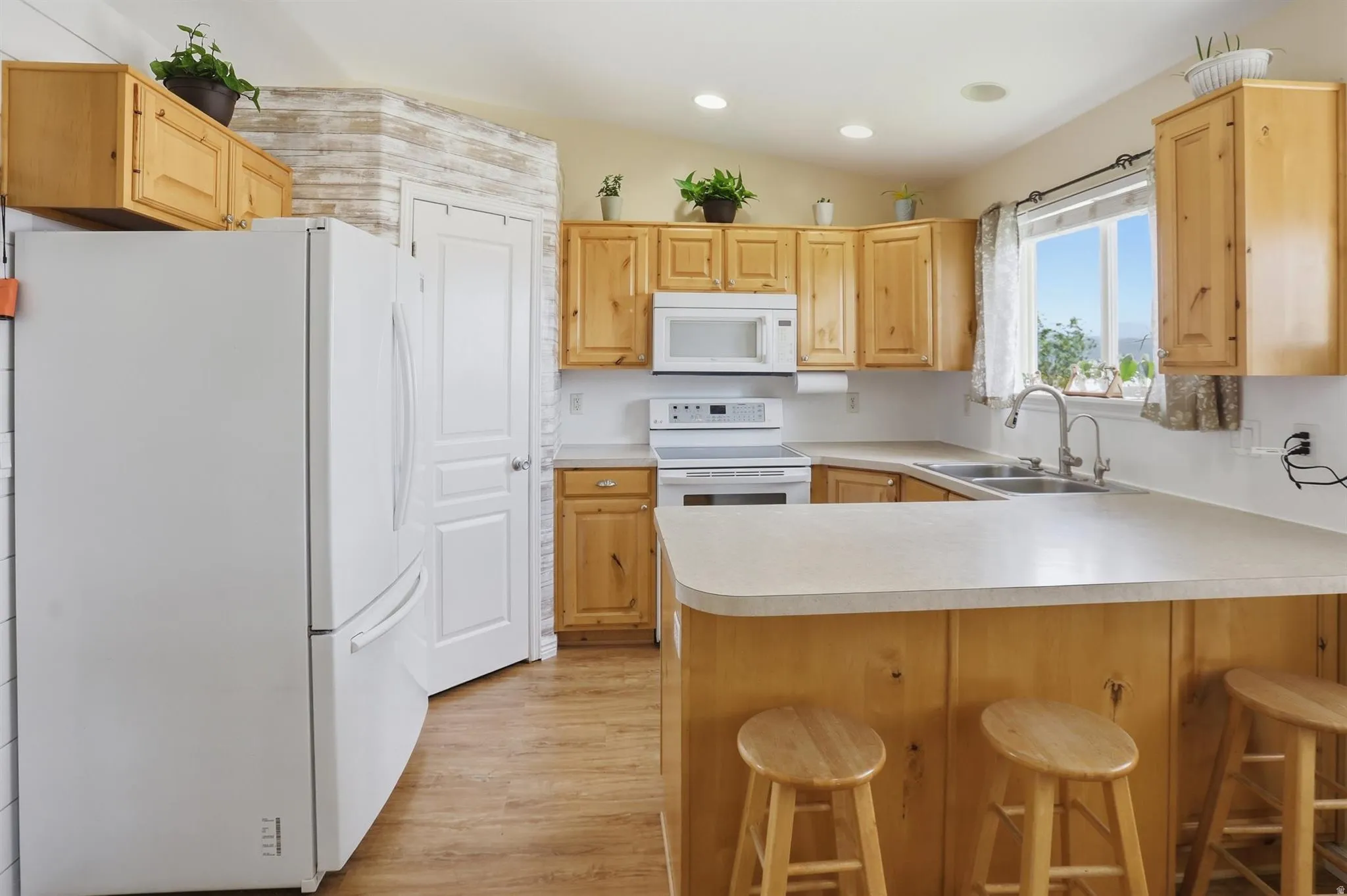 Kitchen featuring wood-finish cabinetry, white appliances, and a double basin sink, pantry