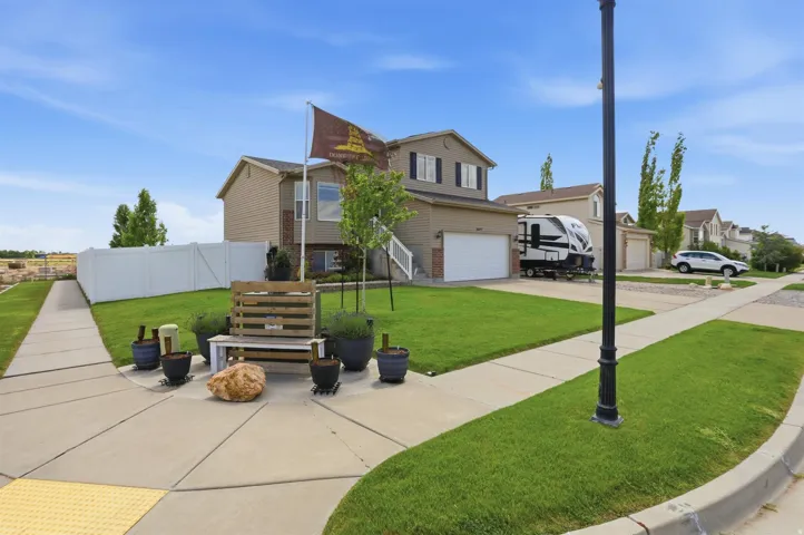 Two-story home with a two-car garage, featuring a tan siding exterior and dark window shutters