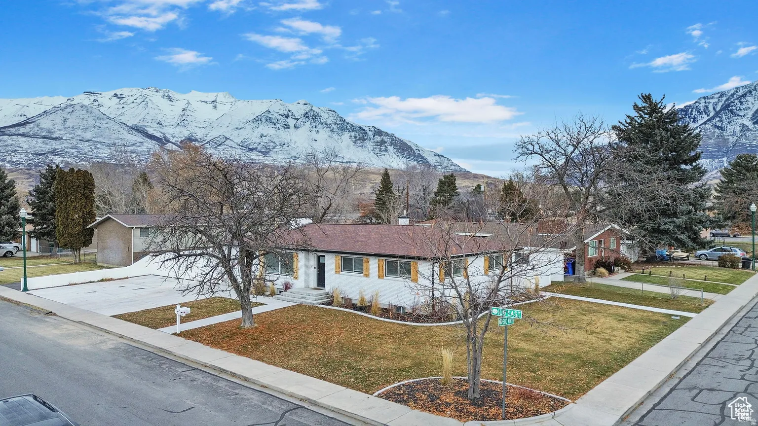 Expansive mountain scenery framing a single-story residence with a brown roof and white exterior