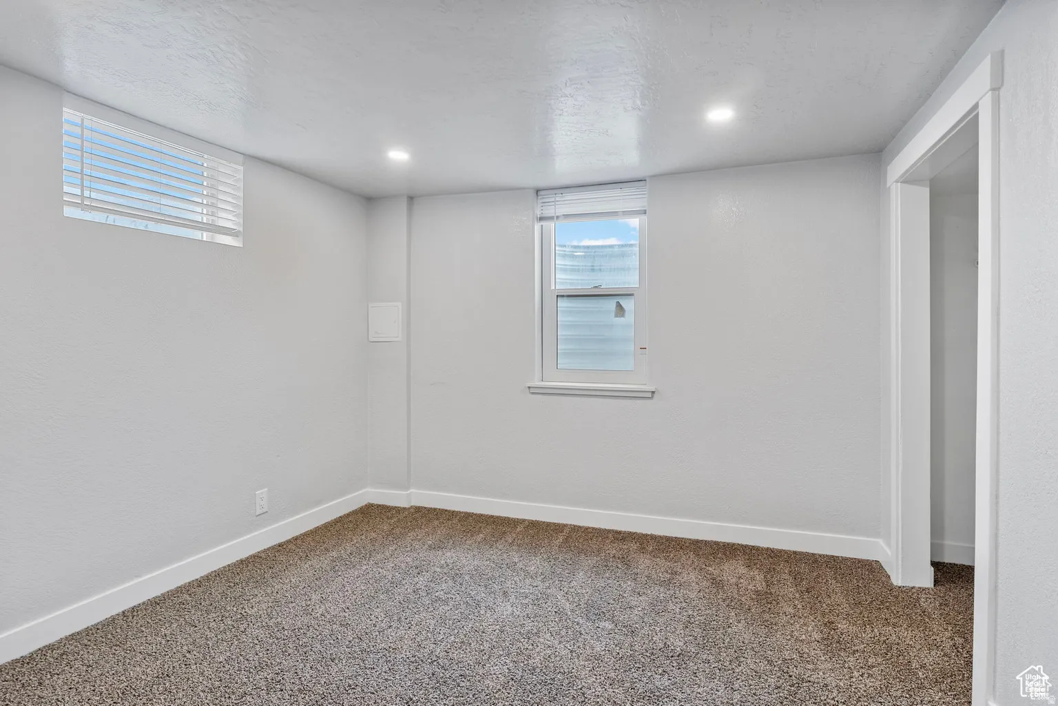 Carpeted room featuring a white painted textured wall finish, white trim, recessed lighting, and two windows