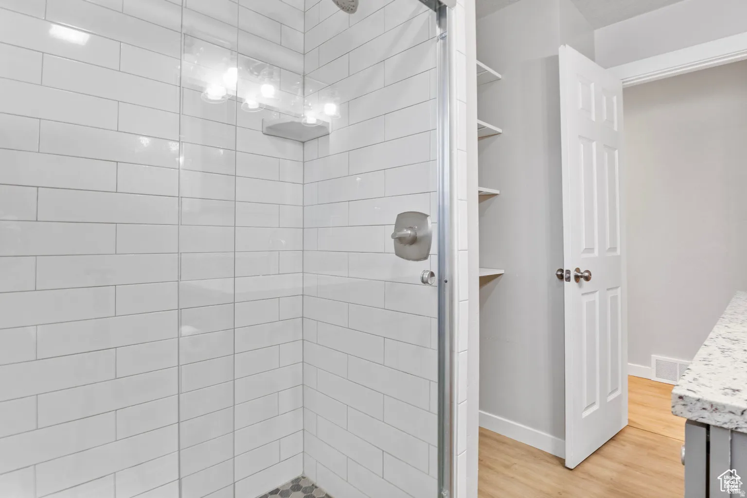 Walk-in shower with white subway tile surround, clear glass enclosure, and brushed nickel fixtures