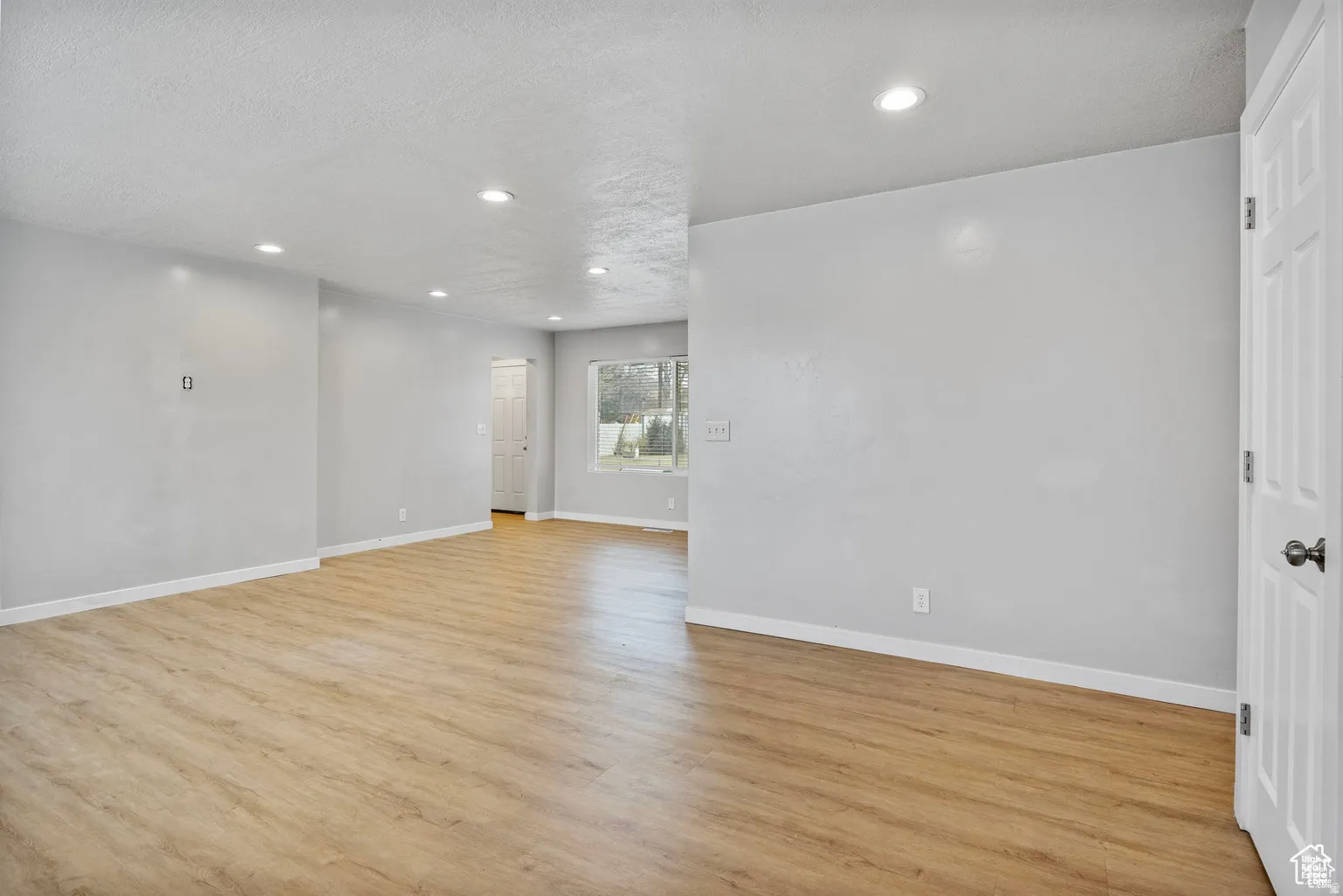 Spacious interior with light wood-finish flooring and recessed ceiling lighting