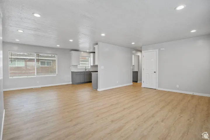 Open-concept living area featuring wood-finish flooring, recessed lighting, and light gray walls