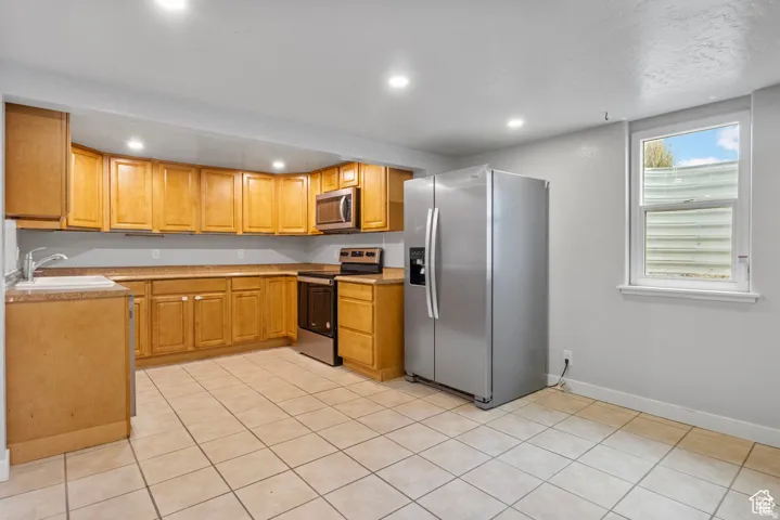 Well-appointed kitchen featuring light wood cabinetry, a stainless steel side-by-side refrigerator, and a stainless steel oven with a microwave