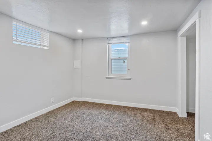 Carpeted room featuring a white painted textured wall finish, white trim, recessed lighting, and two windows