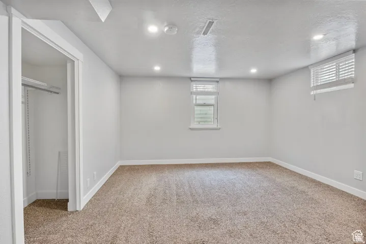 Carpeted room with recessed lighting and two windows featuring blinds