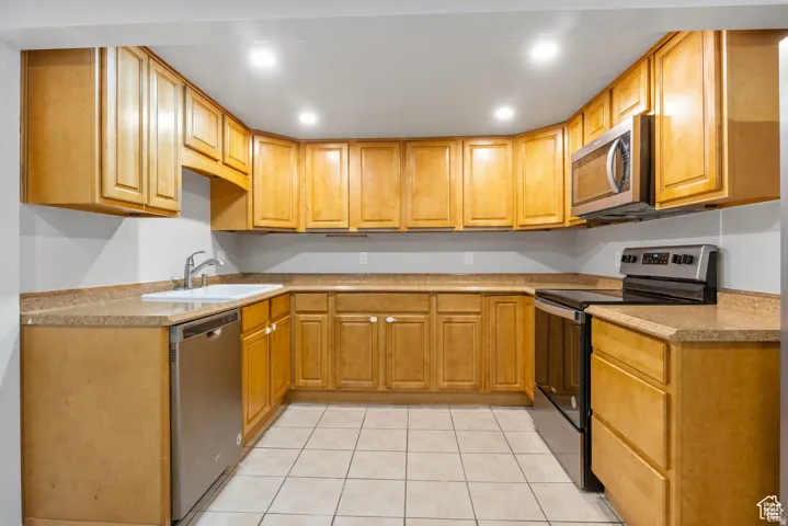 U-shaped kitchen featuring wood-finish cabinetry, light-toned countertops, and recessed lighting