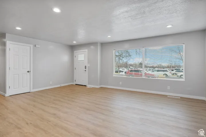 Spacious room featuring wood-finish flooring, recessed lighting, and a neutral color palette