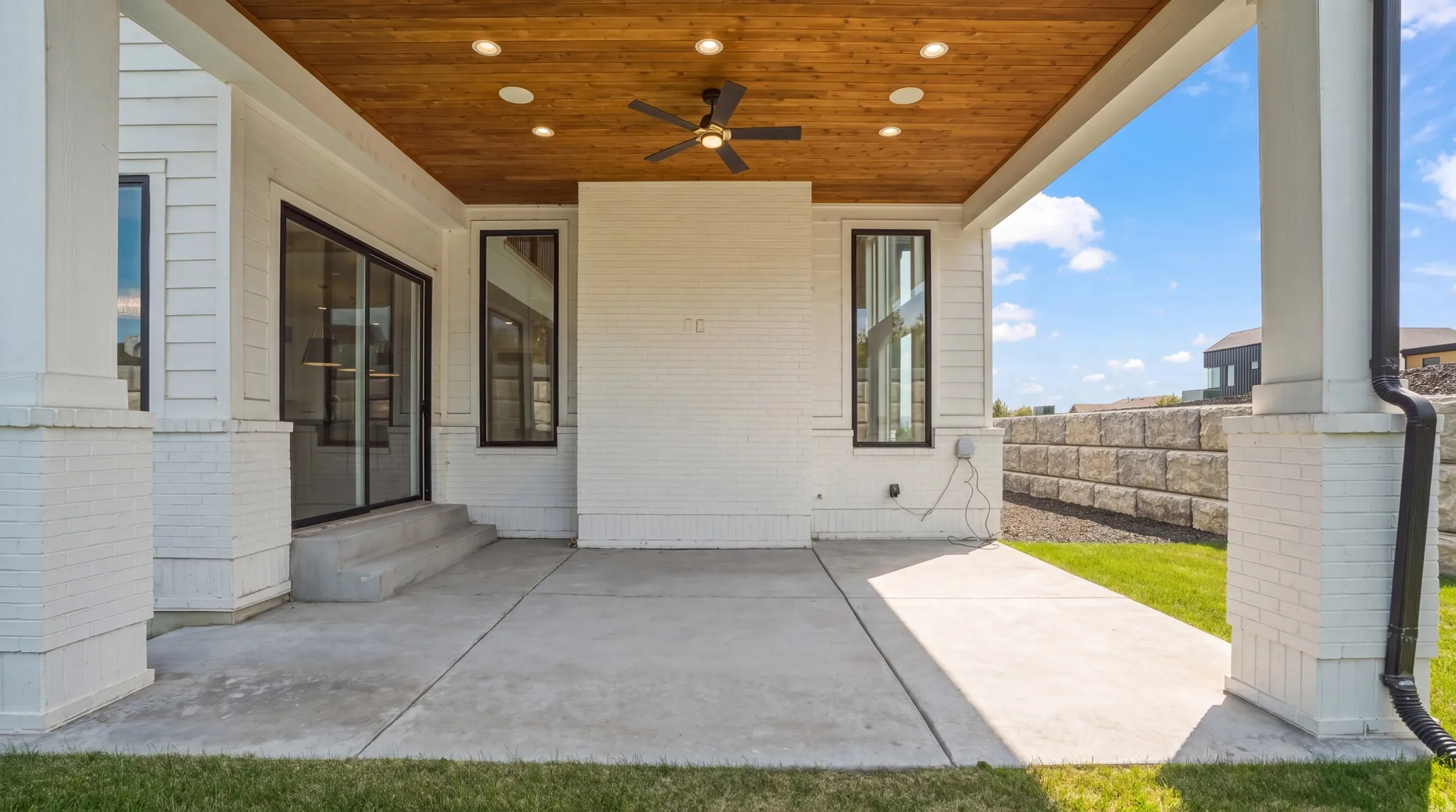 Covered concrete patio with a wood-finish ceiling, recessed lighting, and a ceiling fan