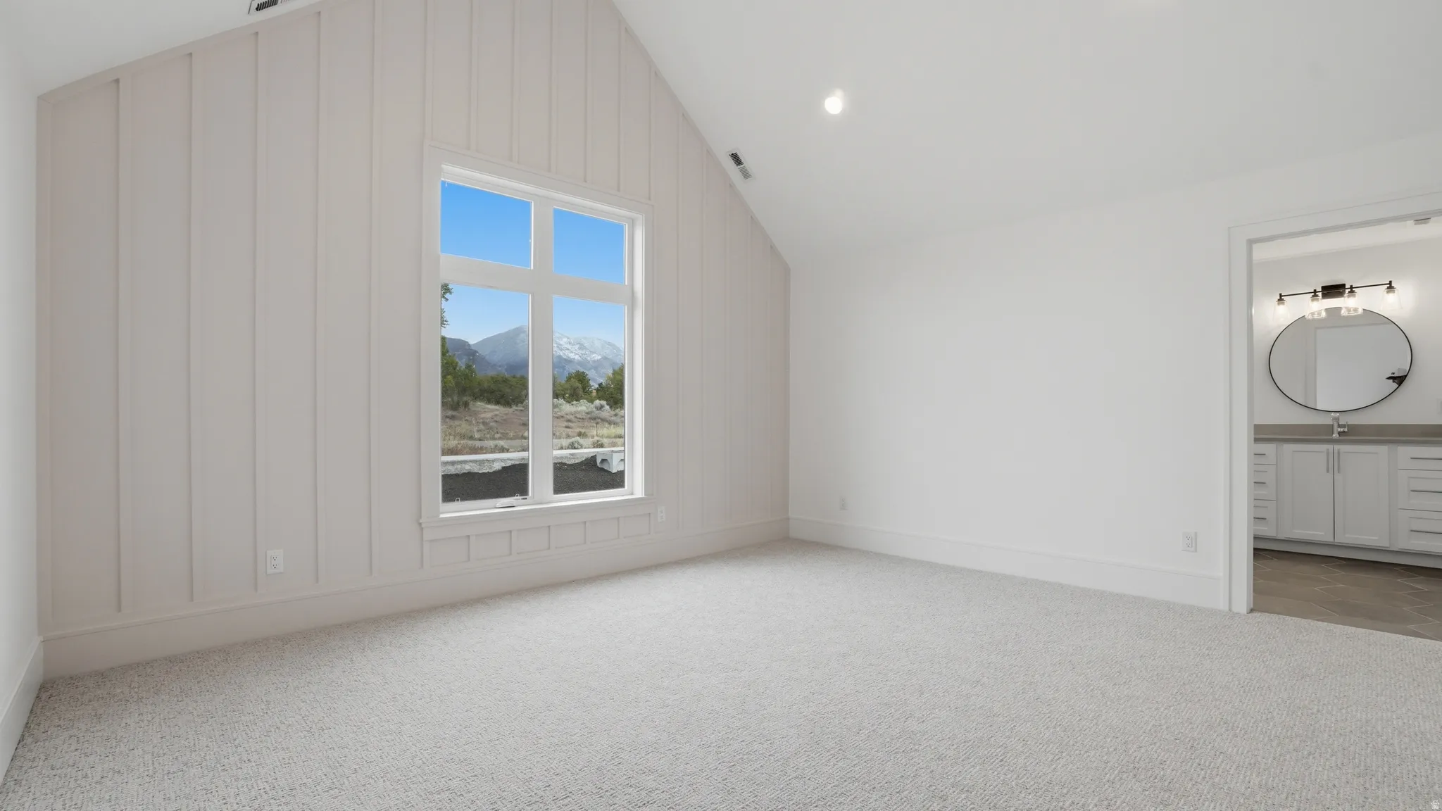 Spacious room featuring vaulted ceilings, board and batten wall detailing, and a large picture window