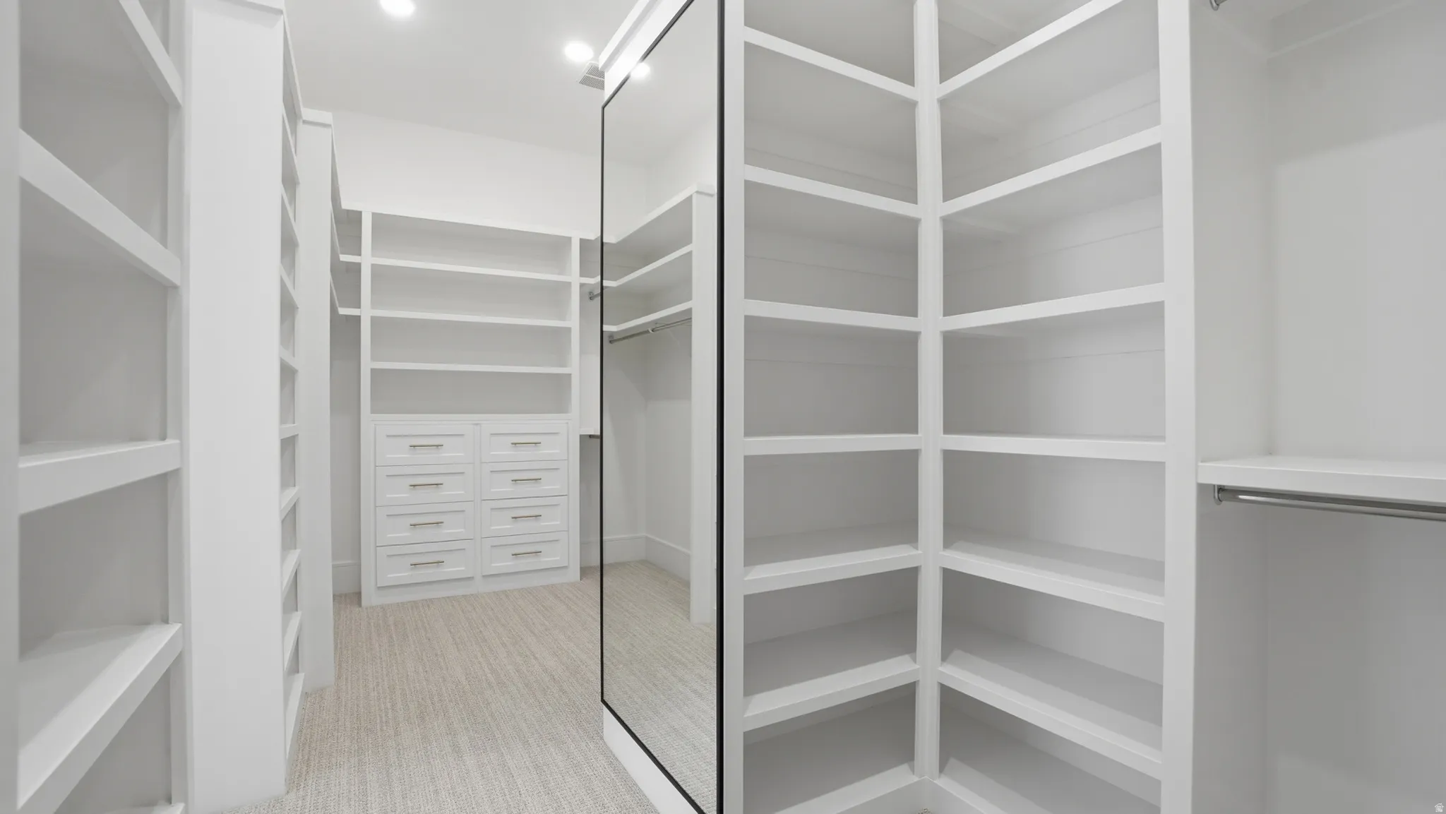 Custom closet system featuring extensive shelving, built-in drawers with modern hardware, and a full-length mirrored door