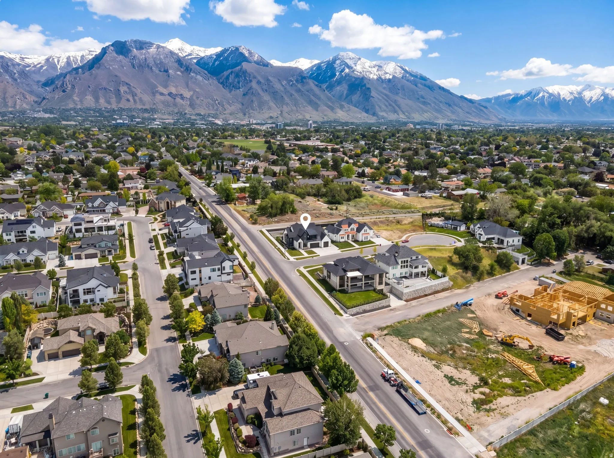 Expansive mountain range backdrop surrounding a residential area with diverse architectural styles, mature trees, and a developed road network