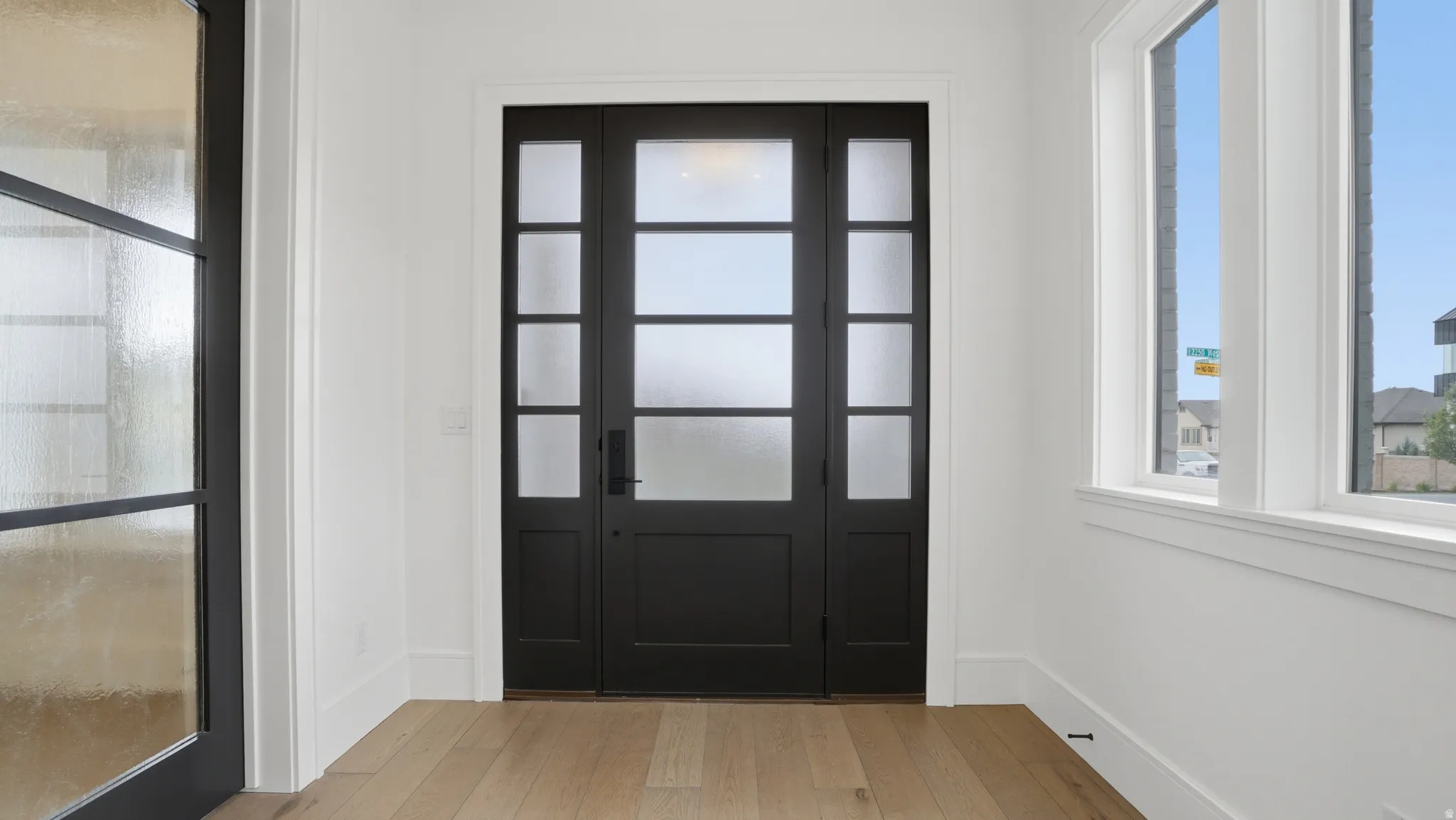 Entryway featuring a black multi-paneled door with frosted glass, flanked by matching sidelights and transom