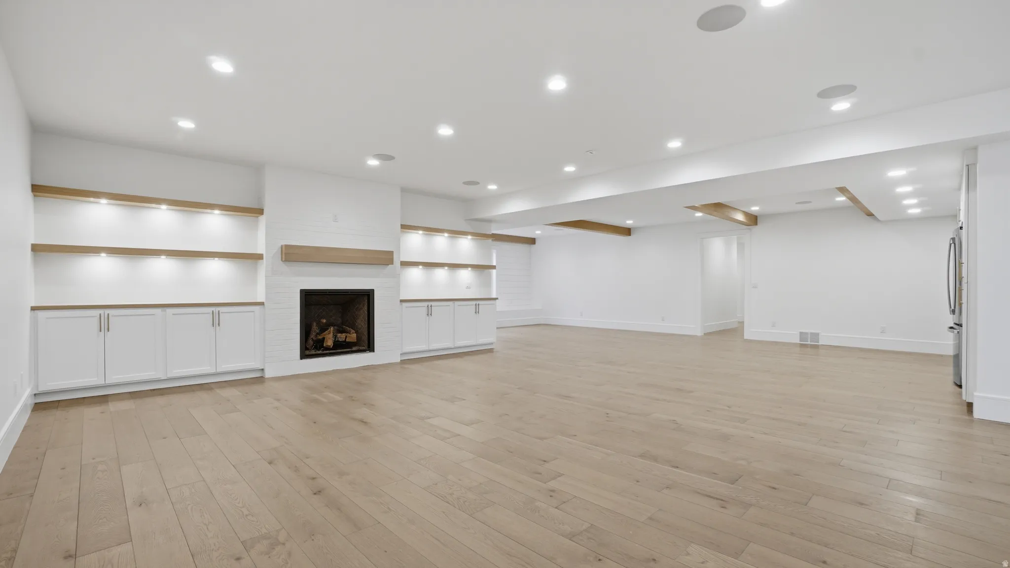 Spacious room featuring wood-finish flooring, recessed lighting, and white walls