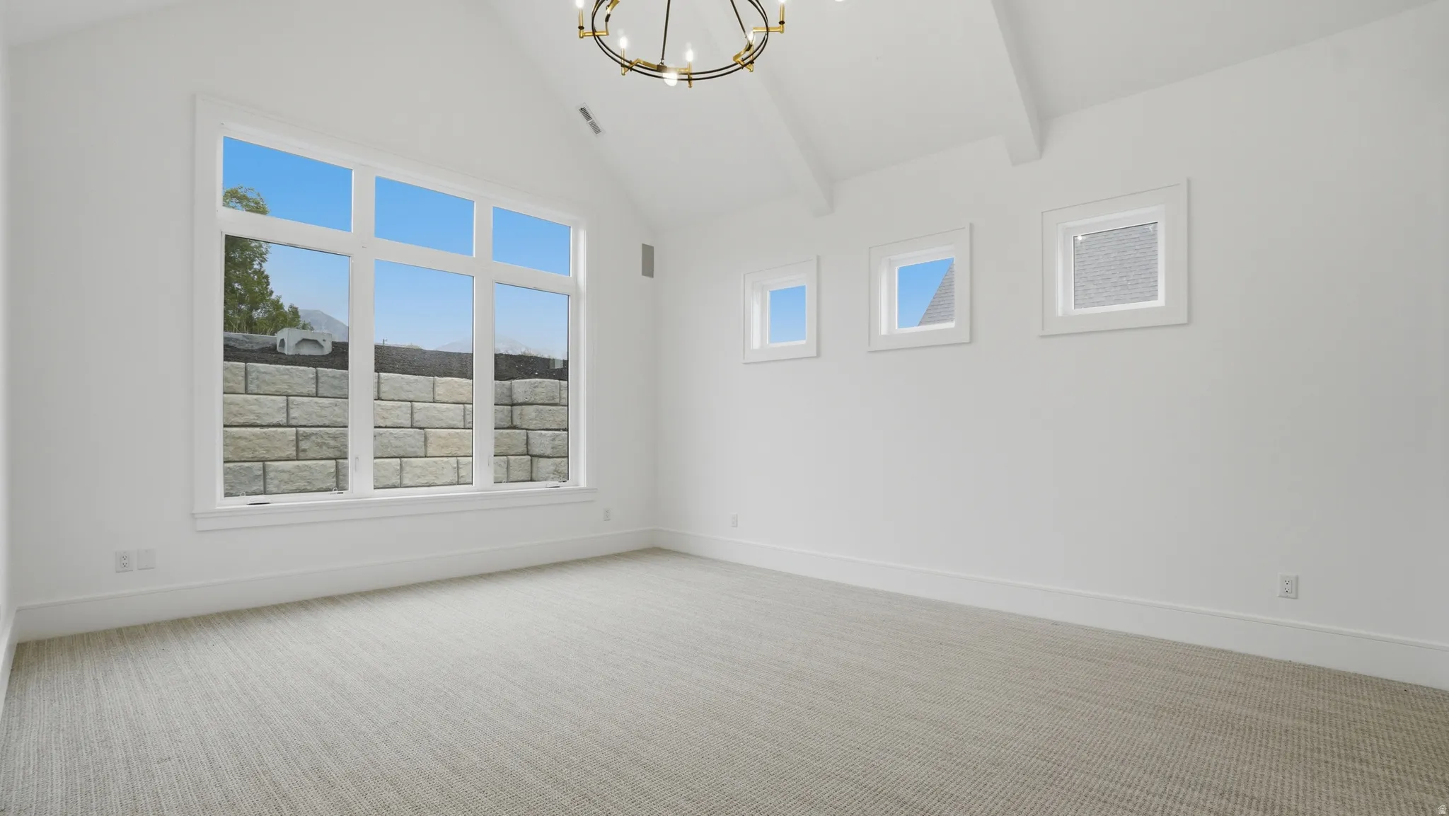 Vaulted ceiling room featuring a large multi-pane window, three additional square windows, and a sophisticated chandelier