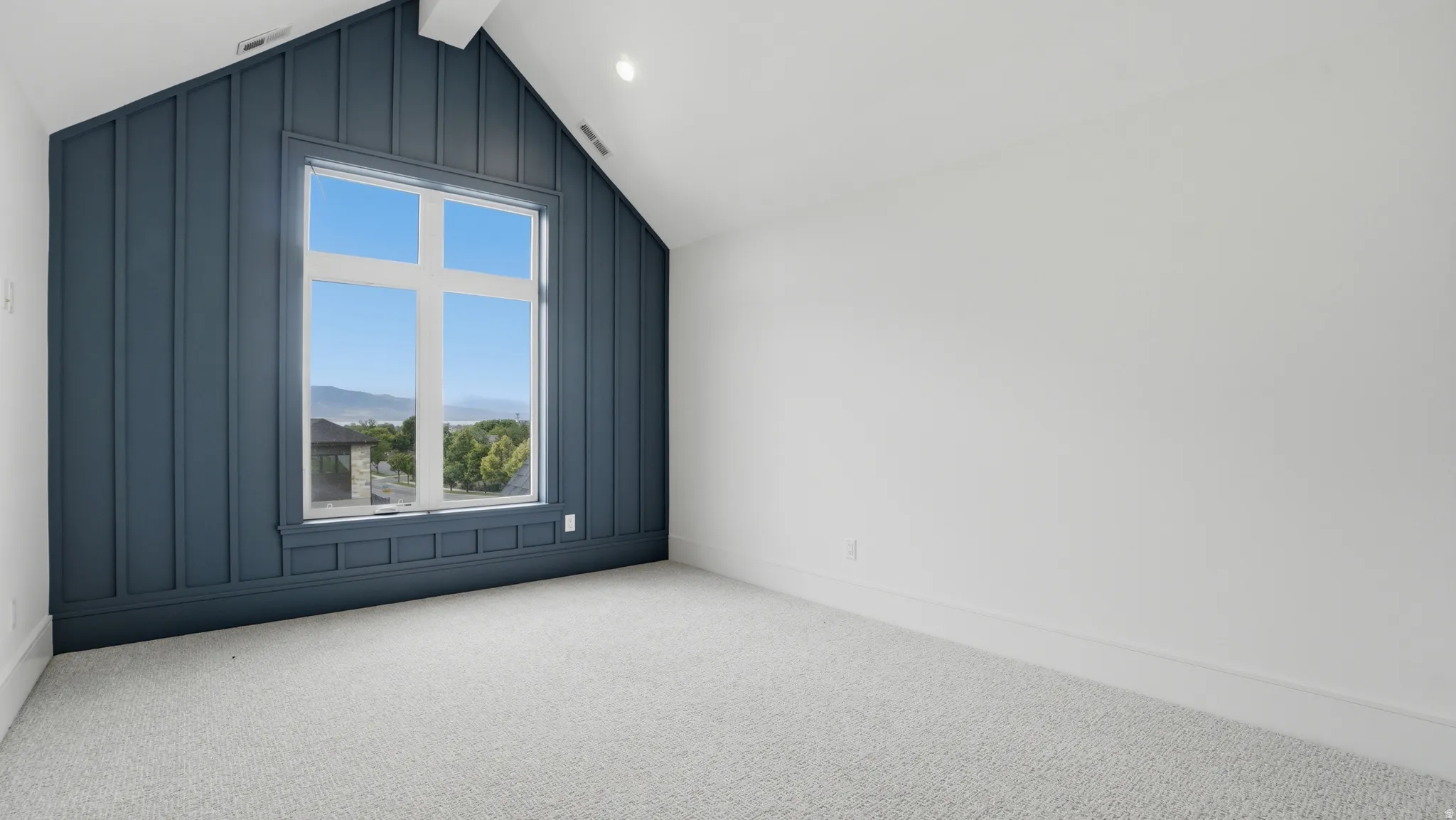 Room featuring a prominent accent wall with vertical paneling and an integrated large window