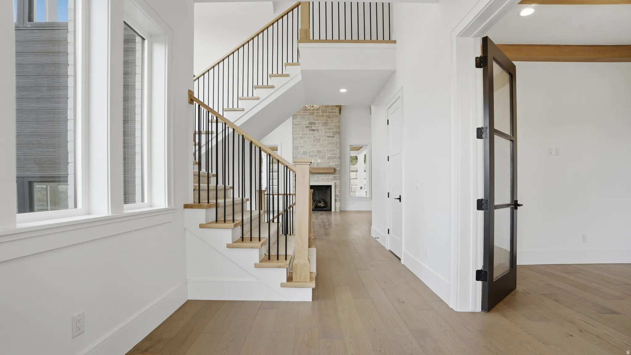 Foyer featuring light wood-finish flooring, a contemporary staircase with black metal balusters and a wood handrail, and white trim