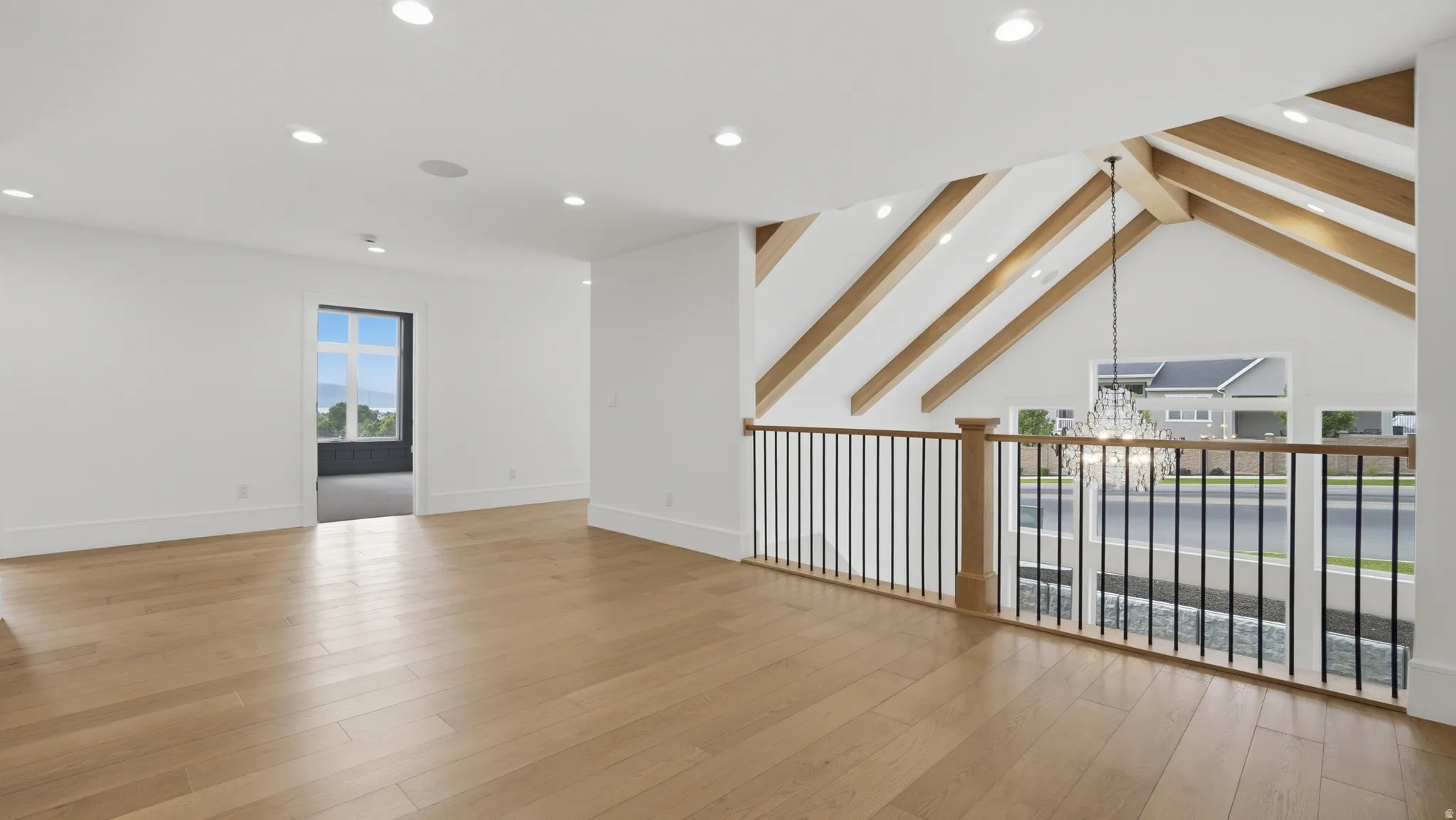 Spacious upper-level area featuring light wood-finish flooring, recessed lighting, and a white color palette