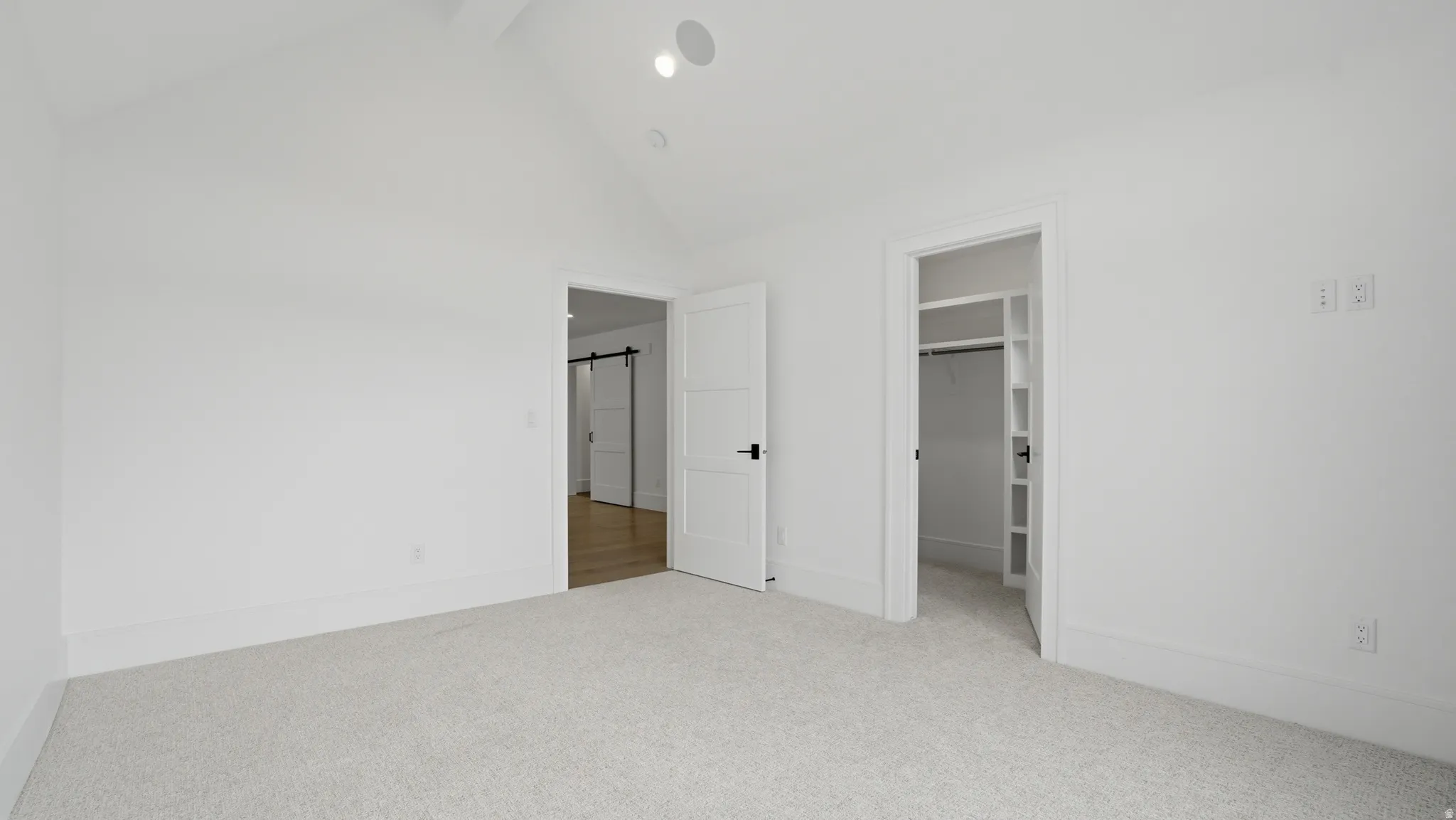 Carpeted room with a vaulted ceiling, recessed lighting, and a built-in closet with shelving