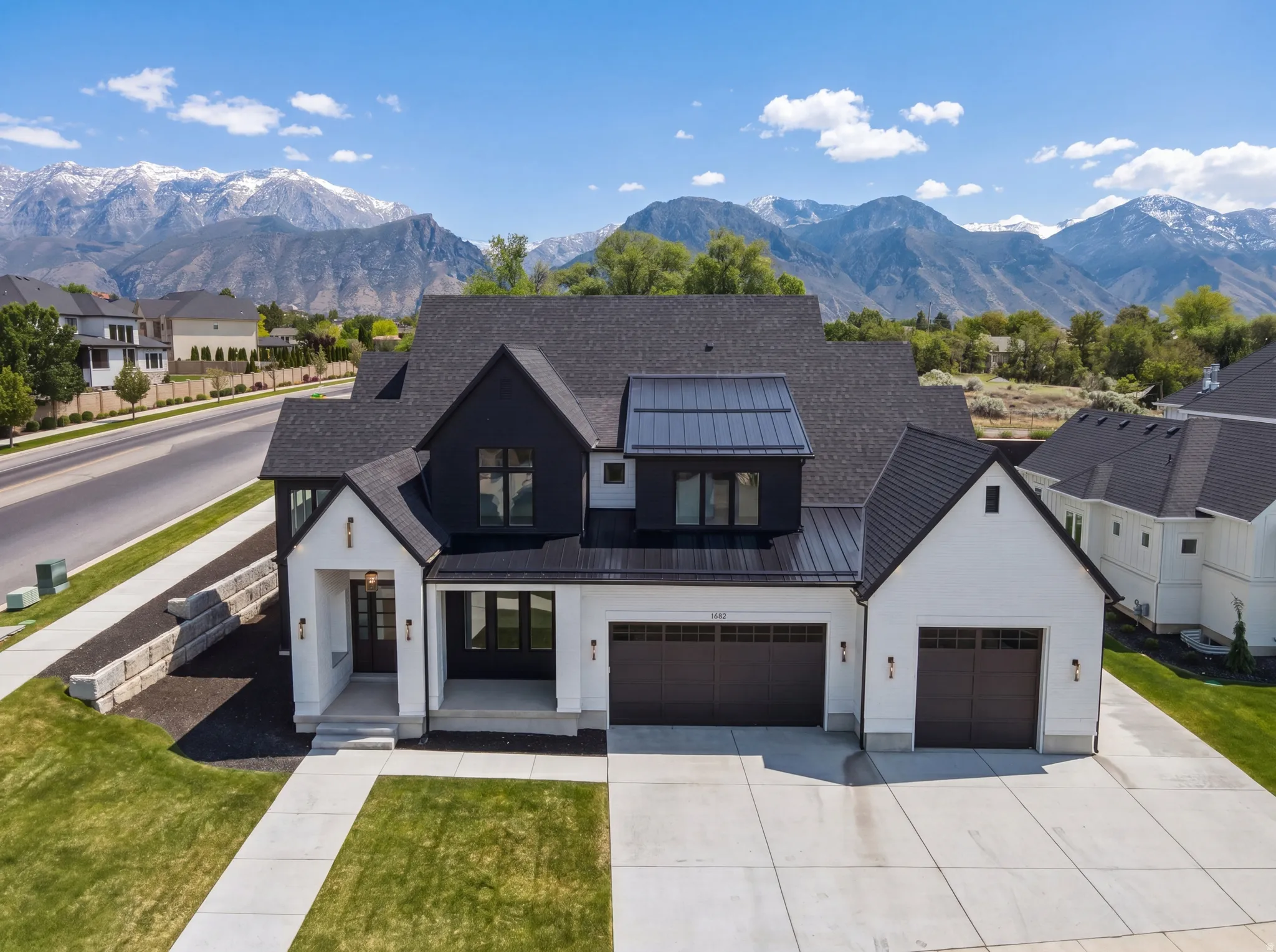 Modern Farmhouse architecture featuring white siding with black accents, a dark asphalt shingle roof, and a metal roof dormer