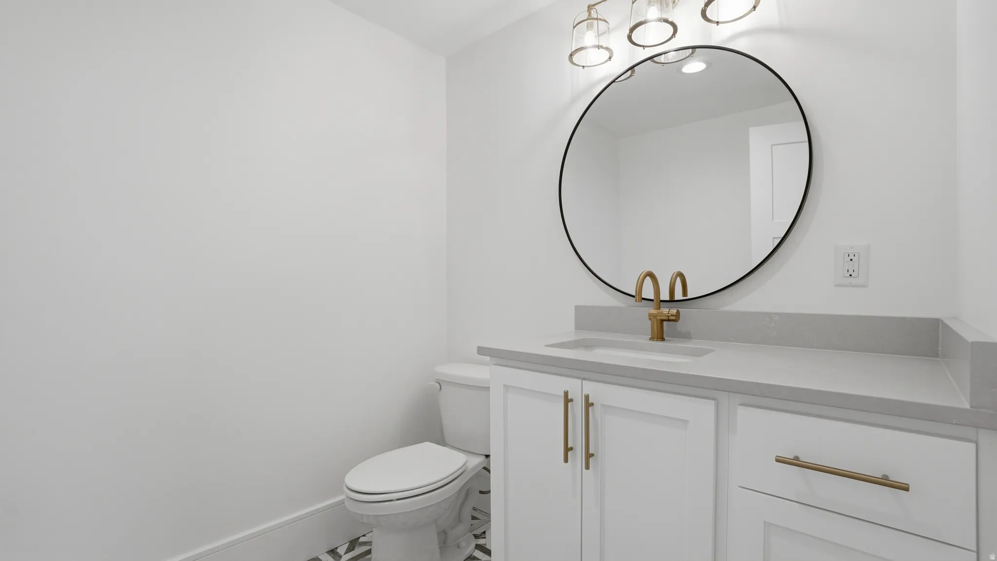 Vanity featuring a built-in sink, light gray countertop, and white cabinetry with gold-finish hardware