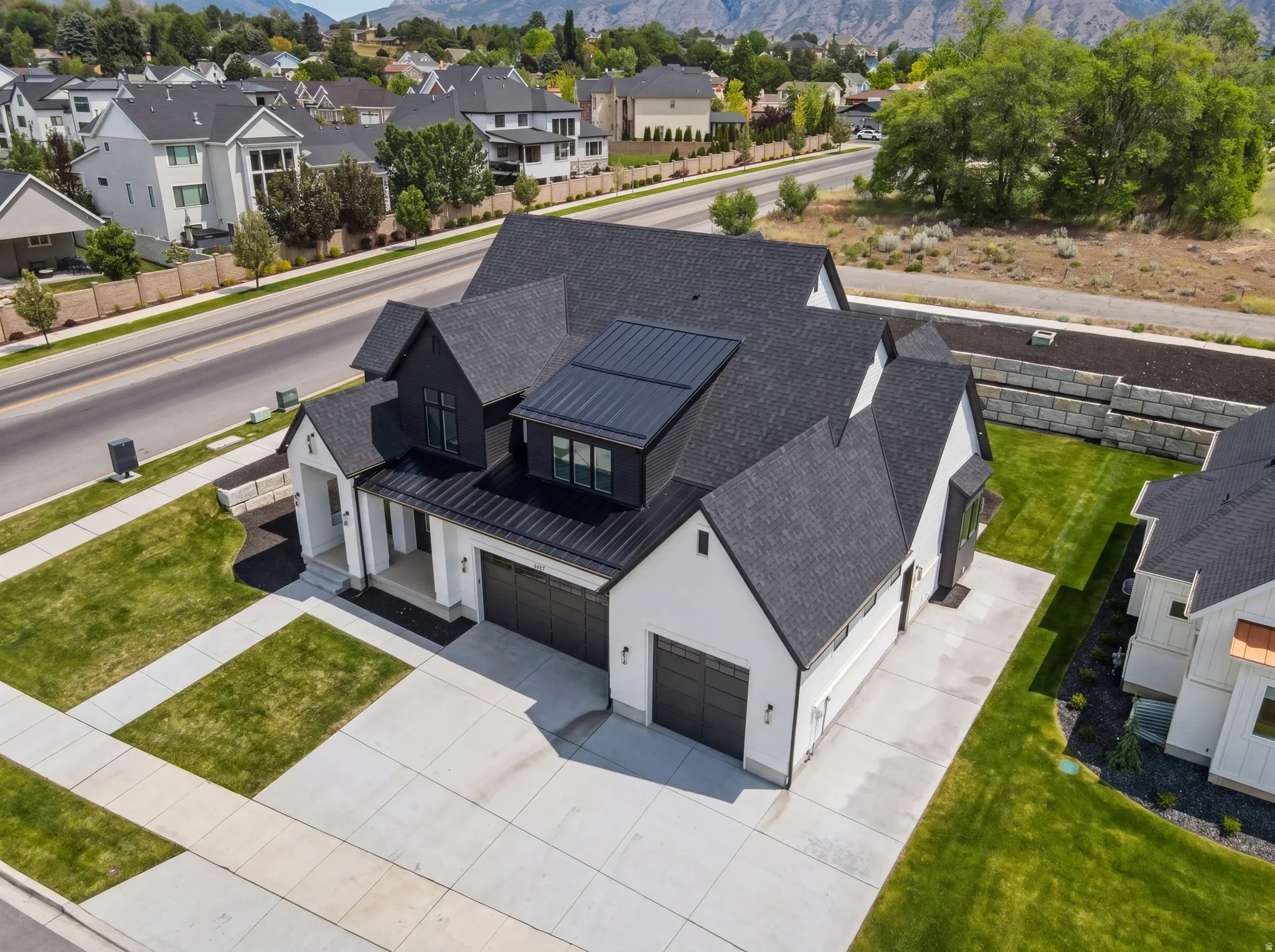 Modern farmhouse exterior featuring a white facade with black trim, multiple gables, and a black shingle roof