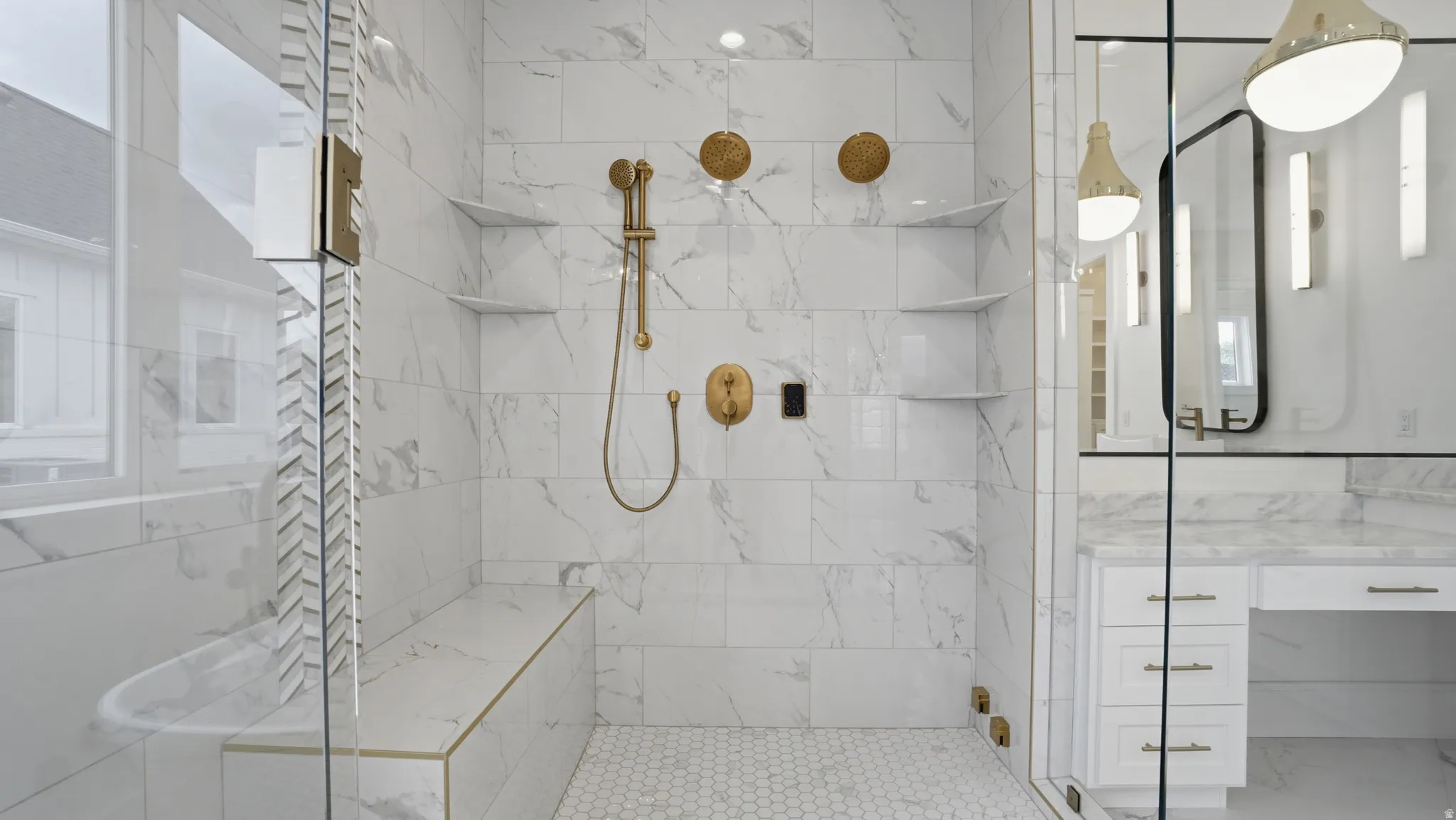 Walk-in shower with full height stone-look tile, hexagonal floor tile, built-in bench with gold-tone trim, and built-in shelving