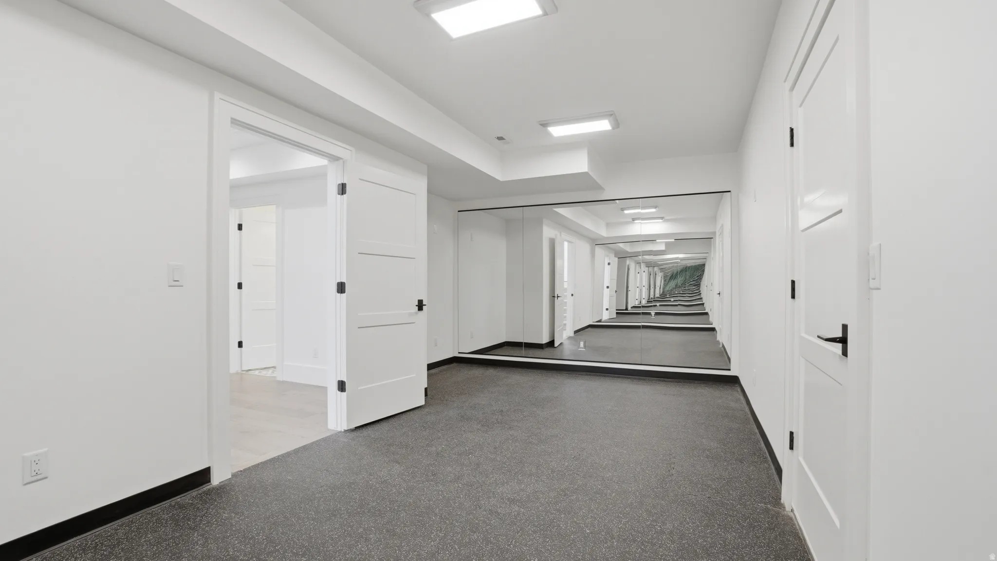 Hallway featuring a full-wall mirror, recessed lighting, and durable flooring