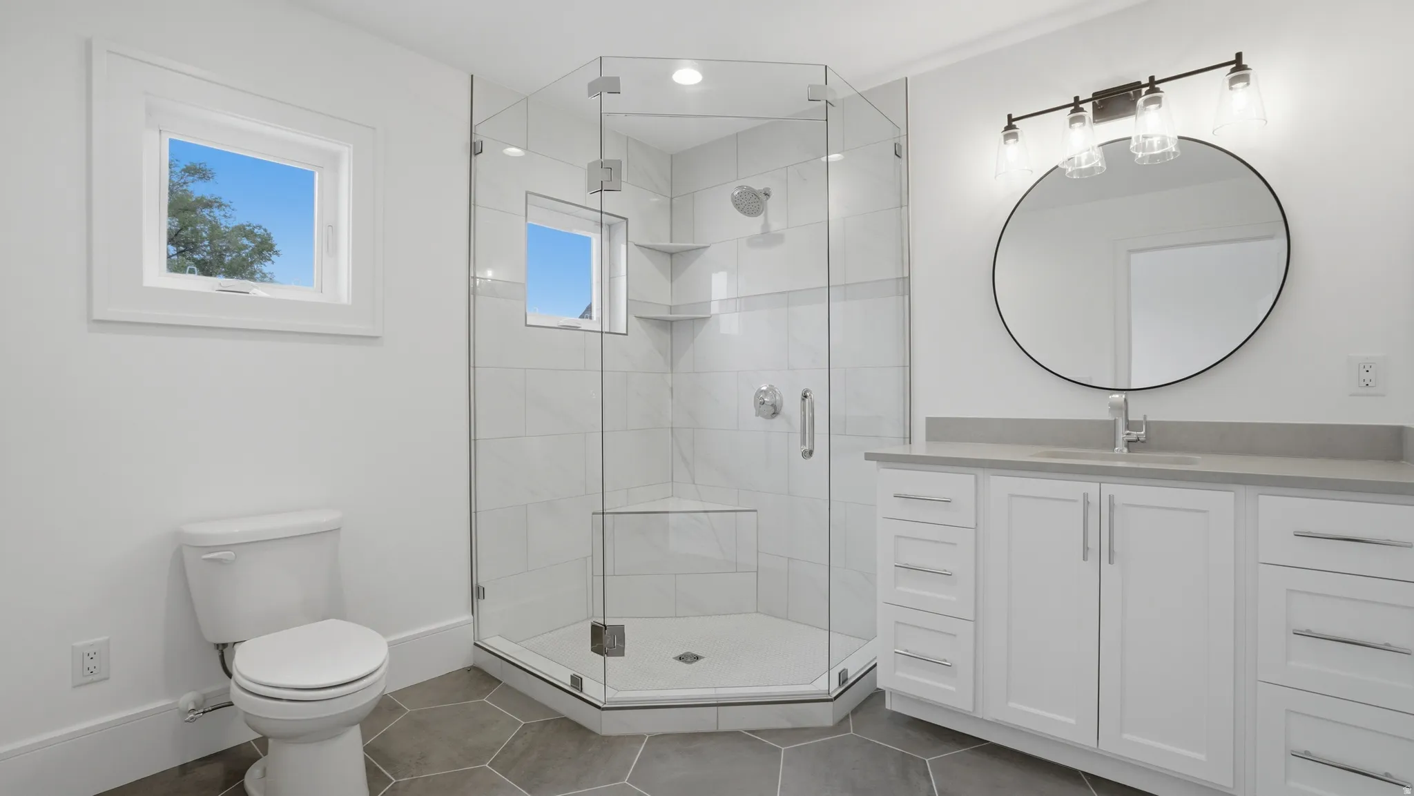 Bathroom featuring a glass-enclosed shower with tile surround, a single vanity with stone countertop, and hexagonal floor tiling