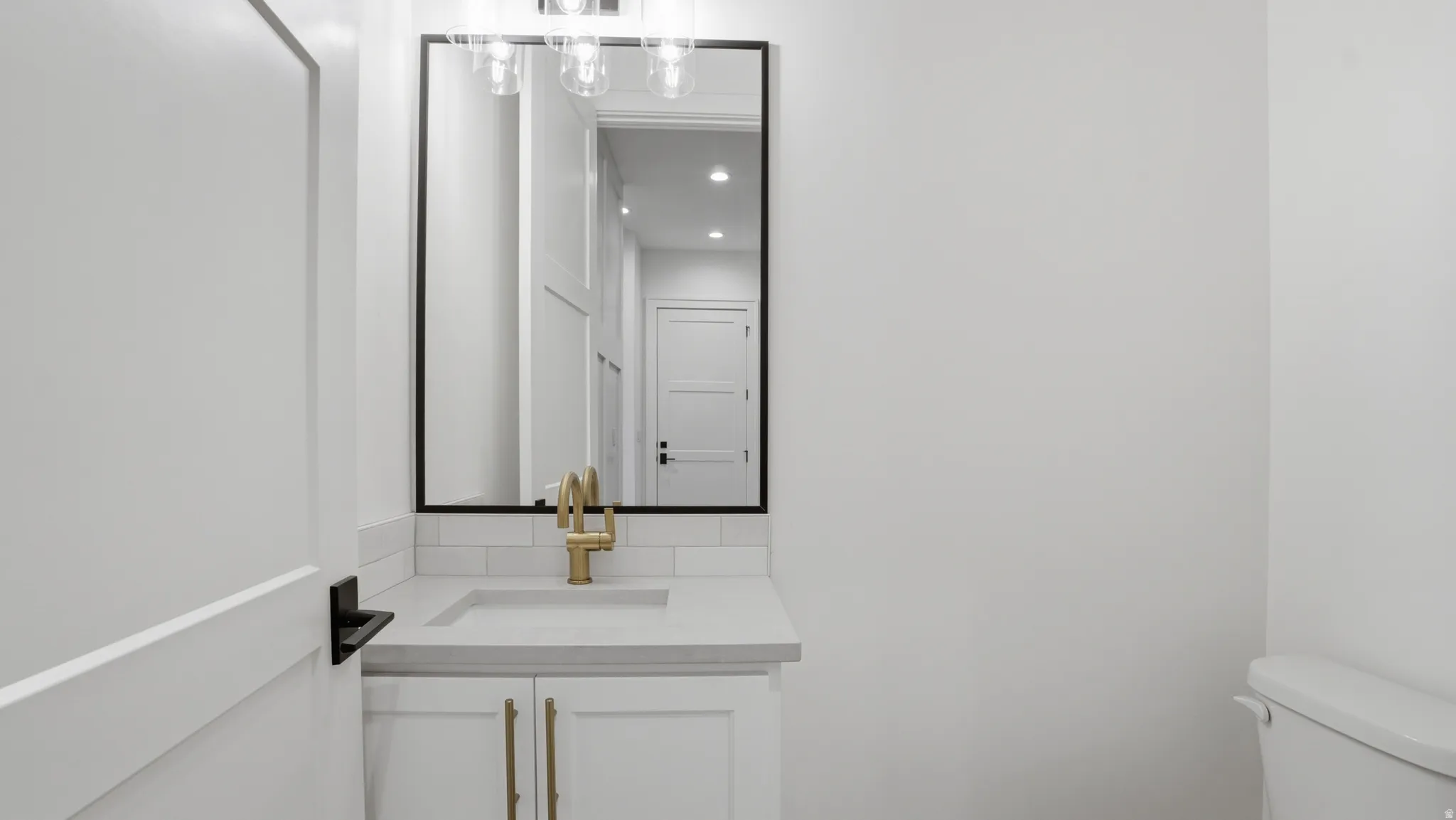 Bathroom vanity featuring a rectangular undermount sink, brass-finish faucet, and coordinating cabinet hardware