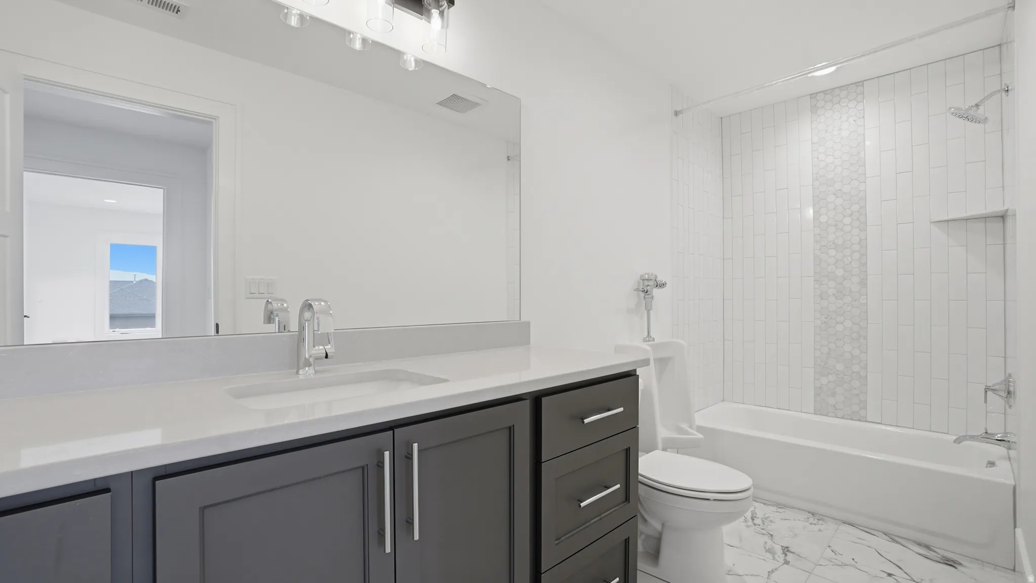 Bathroom featuring a gray vanity with a single under-mount sink, white countertop, and a large wall-mounted mirror