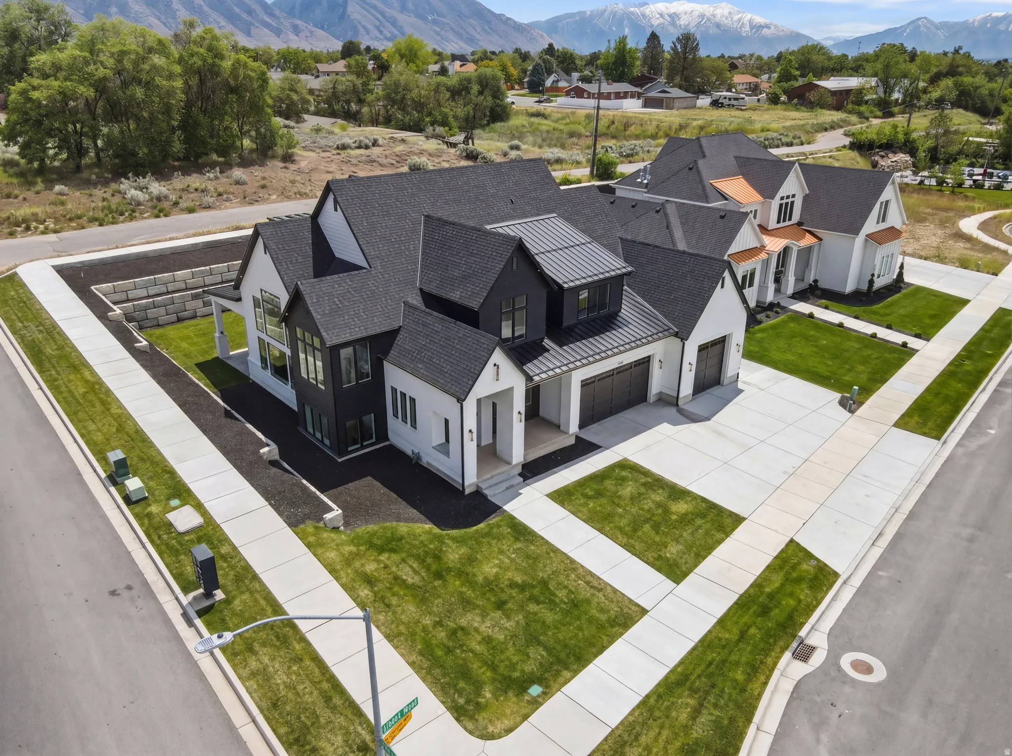 Modern Farmhouse exterior featuring a multi-gable roofline with dark shingles, white siding, black window frames, and an expansive concrete driveway