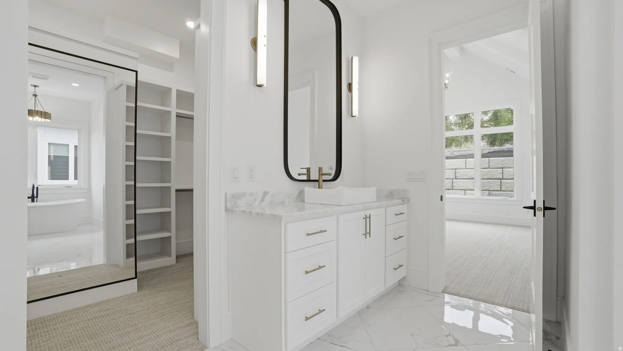 Contemporary vanity featuring a vessel sink with a wall-mounted faucet, a rectangular mirror, and sconce lighting