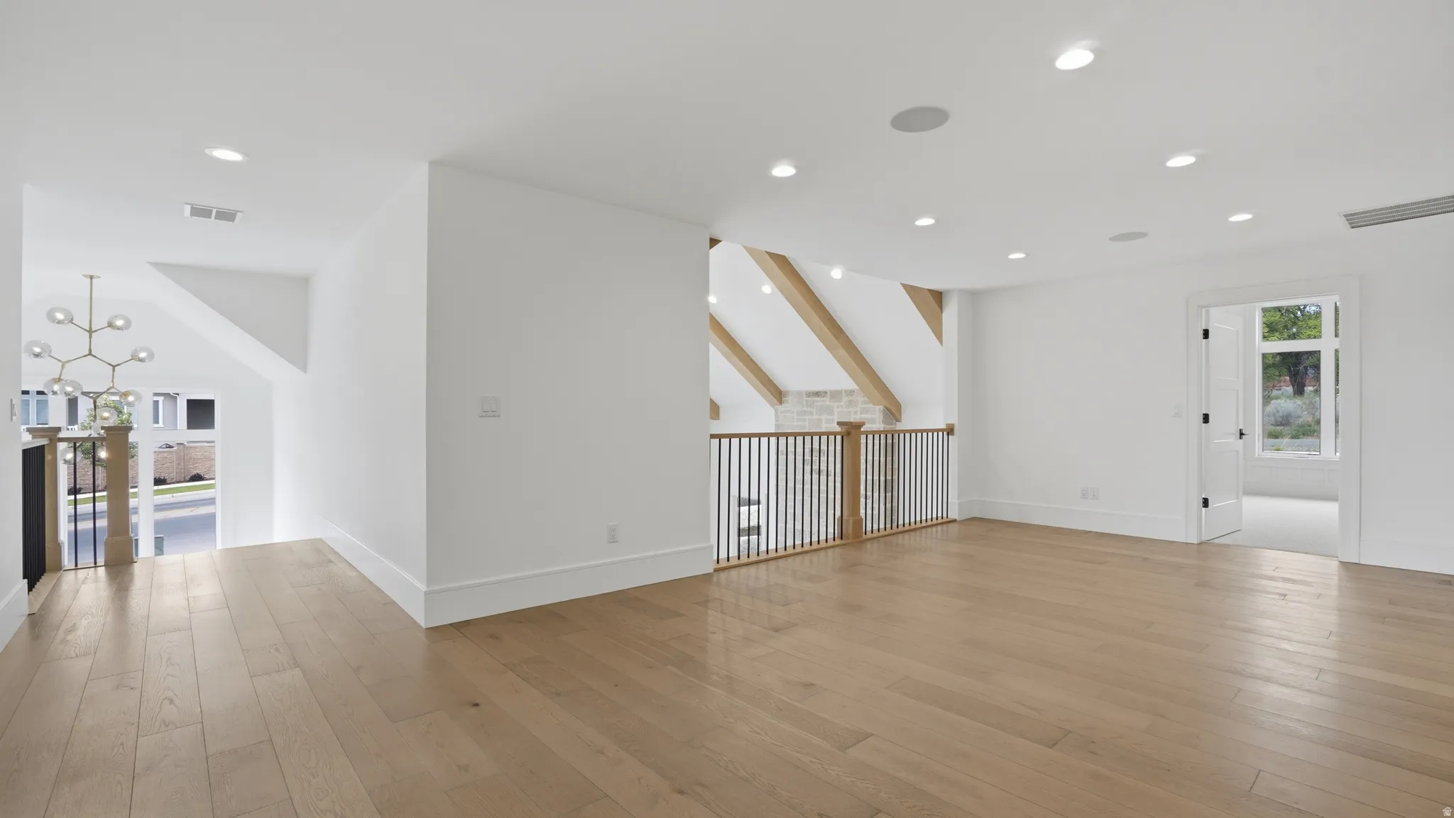 Spacious upper-level area featuring wood-finish flooring, recessed lighting, and a modern chandelier