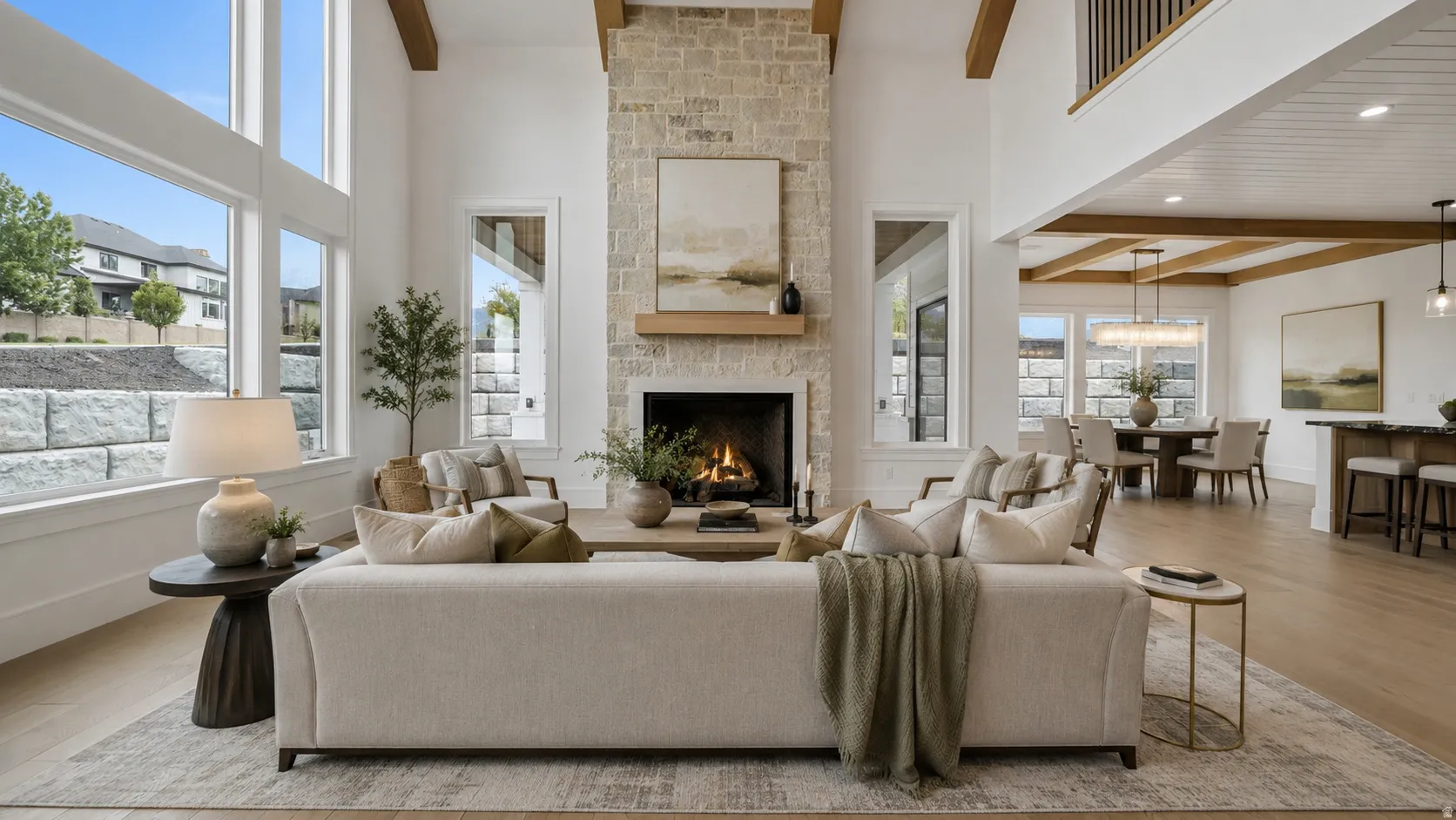 Great room with a stone-clad fireplace and wood mantle, featuring high ceilings with exposed wood beams