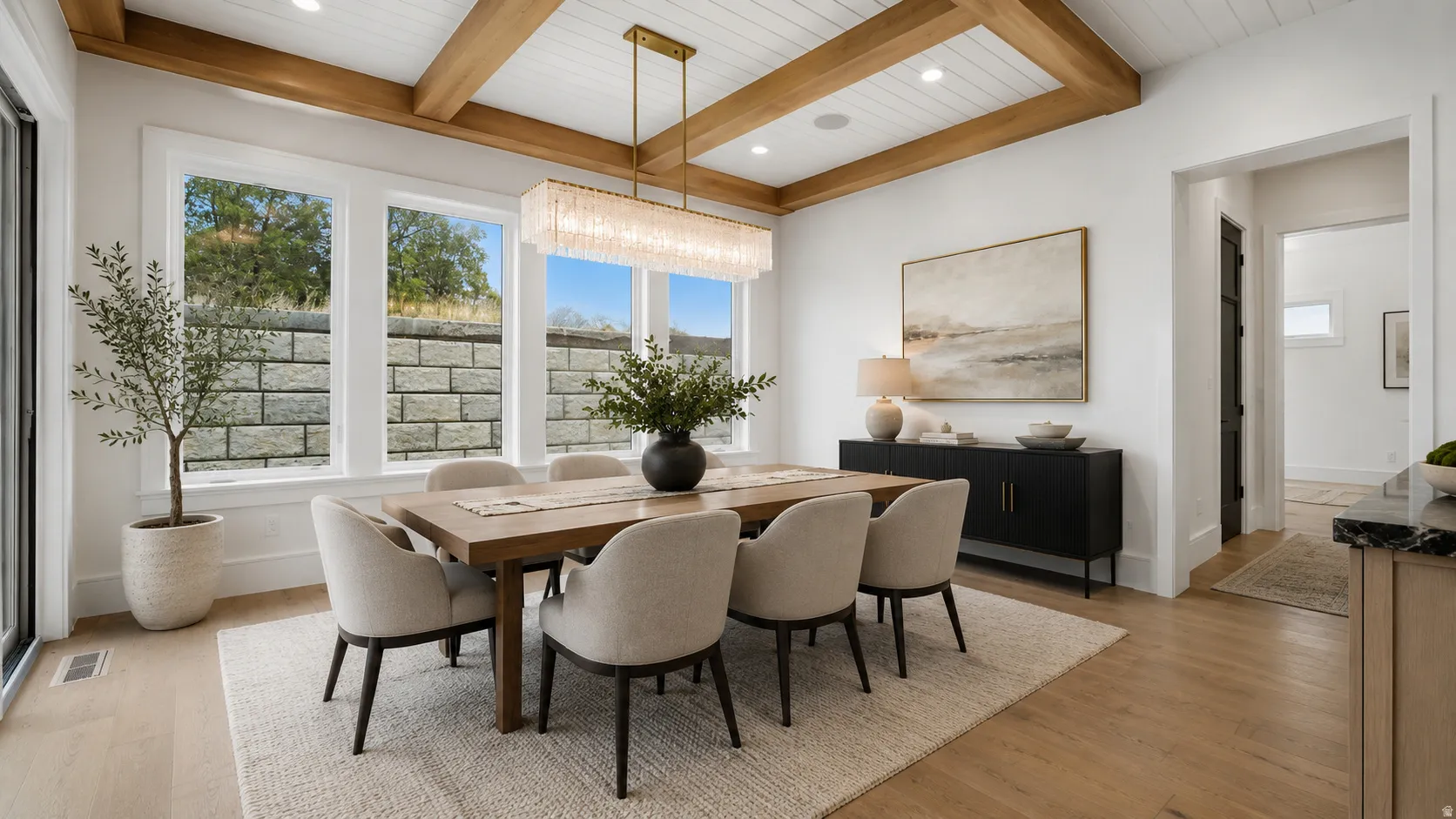Dining area featuring a coffered ceiling with wood beams, a contemporary linear chandelier, wide-plank wood-finish flooring, and multiple large windows