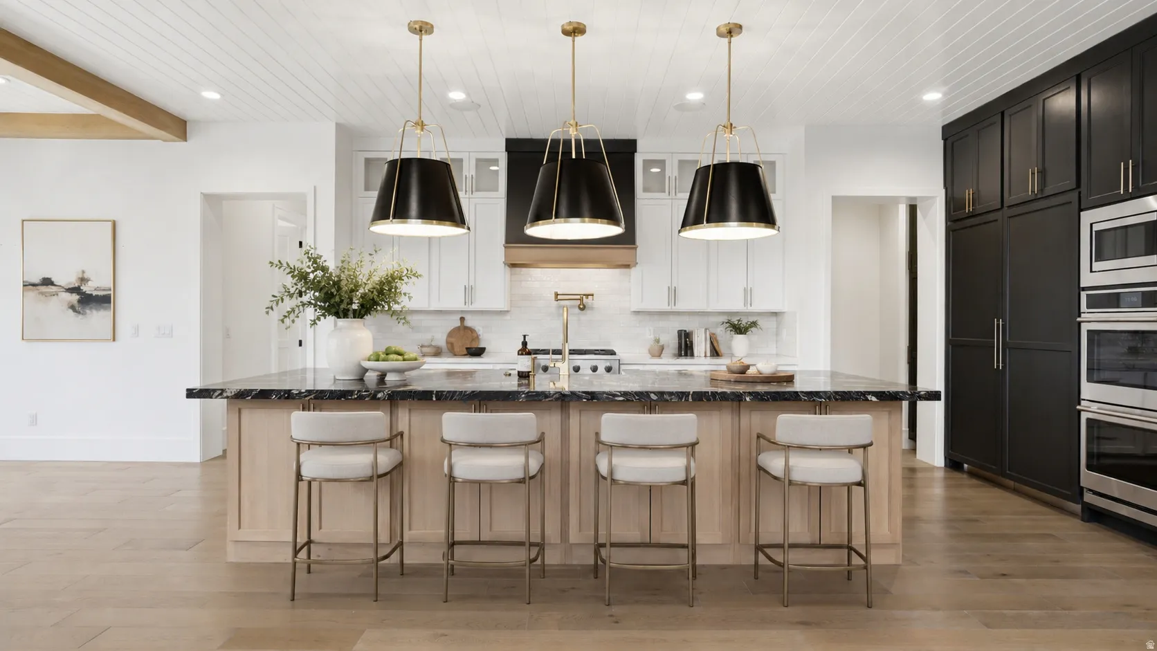 Kitchen featuring a large island with dark stone countertop, light wood-finish cabinetry, and three pendant light fixtures
