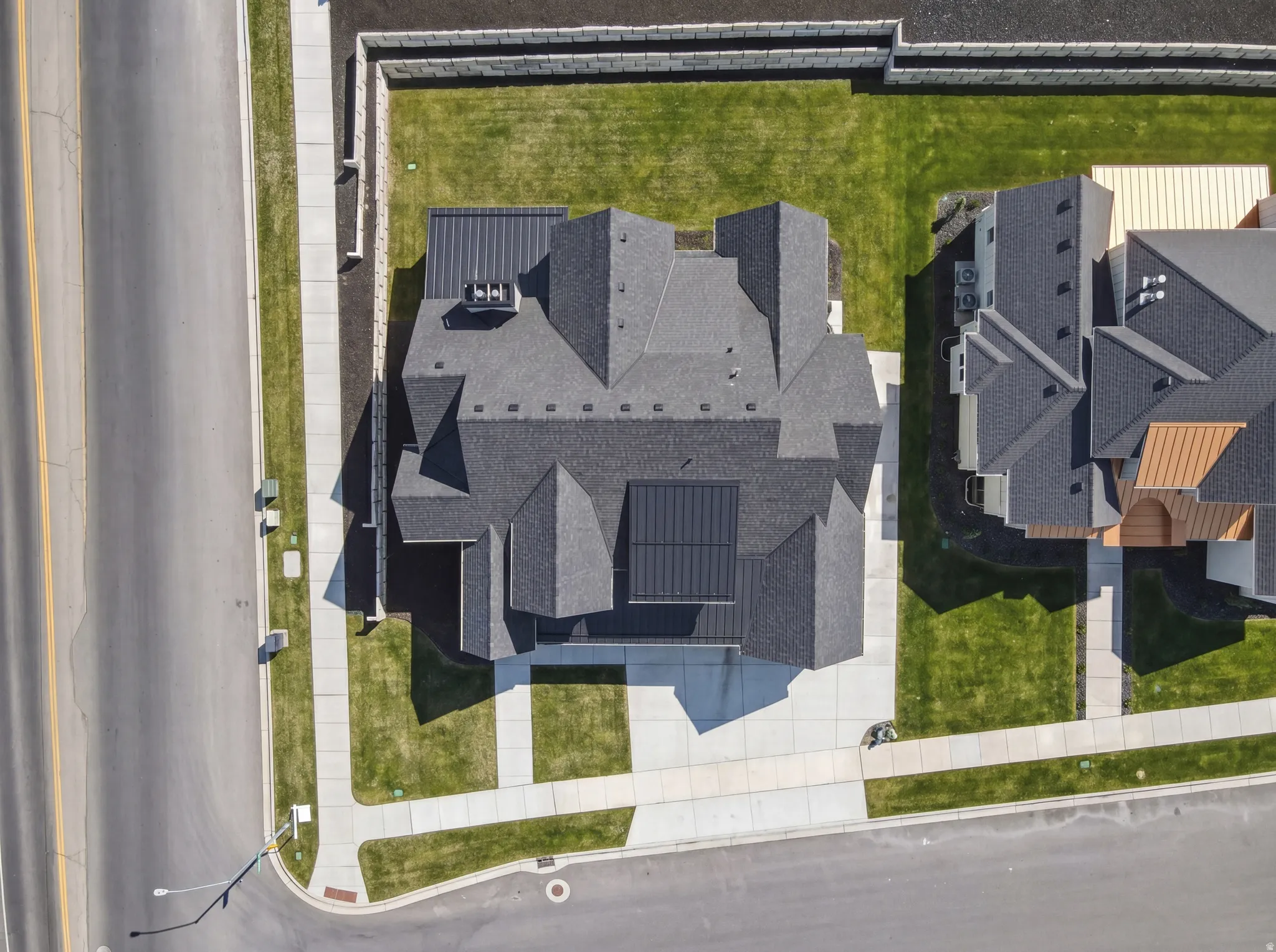 Modern residential property featuring a multi-gabled dark shingle roof with integrated solar panels and a contrasting dark metal roof section