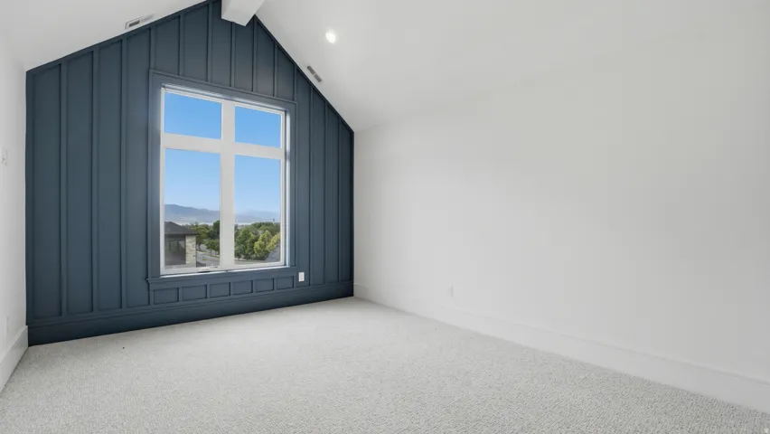 Room featuring a prominent accent wall with vertical paneling and an integrated large window