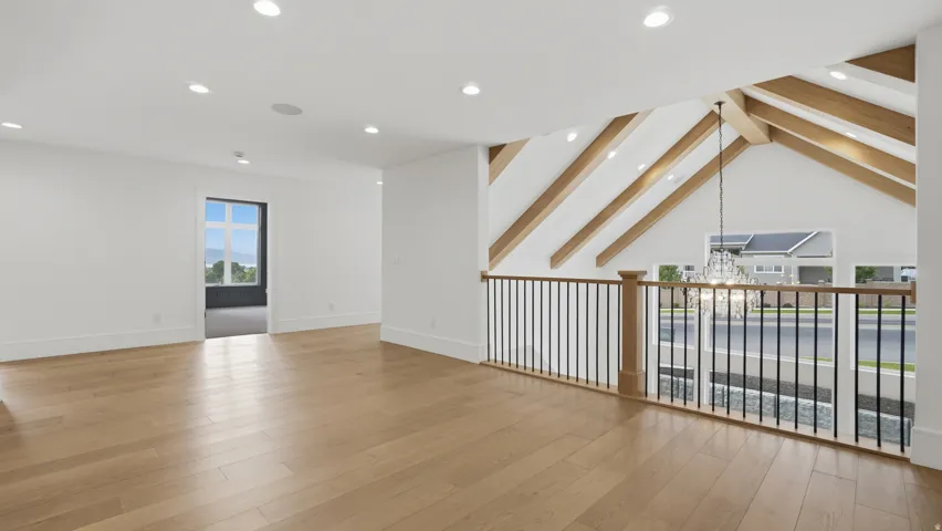 Spacious upper-level area featuring light wood-finish flooring, recessed lighting, and a white color palette