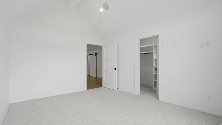 Carpeted room with a vaulted ceiling, recessed lighting, and a built-in closet with shelving