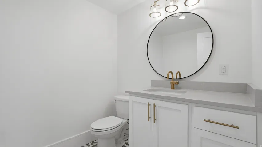 Vanity featuring a built-in sink, light gray countertop, and white cabinetry with gold-finish hardware