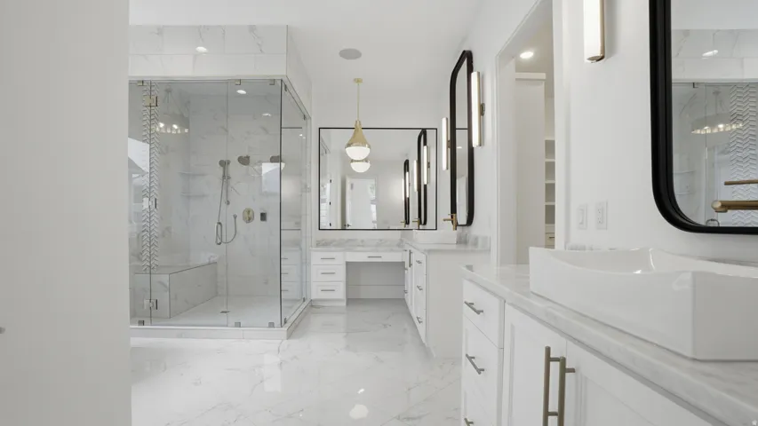 Spacious bathroom featuring a frameless glass shower enclosure with bench seating, dual vanity with vessel sinks, white cabinetry, and large format tiled flooring