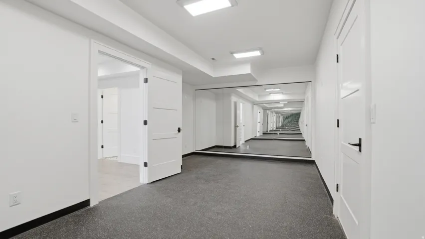 Hallway featuring a full-wall mirror, recessed lighting, and durable flooring
