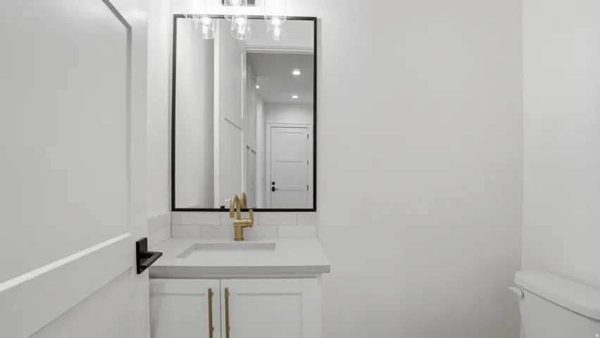 Bathroom vanity featuring a rectangular undermount sink, brass-finish faucet, and coordinating cabinet hardware